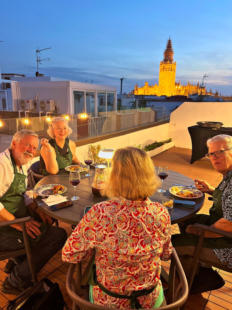 Guests dine on the rooftop terrace with the illuminated Giralda in the background after sunset