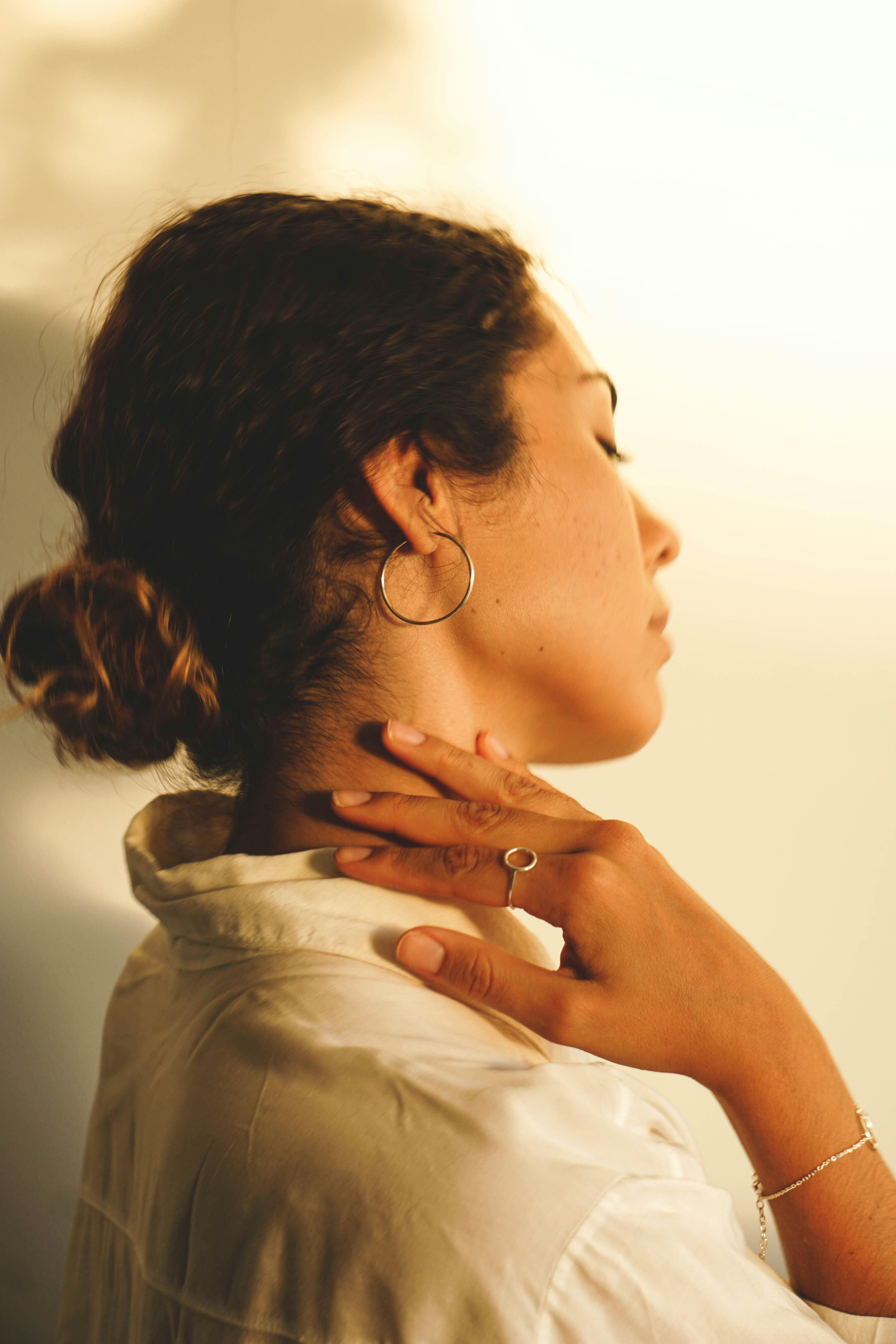 Woman holding her neck with subtle tension, reflecting nervous system stress and tight shoulders