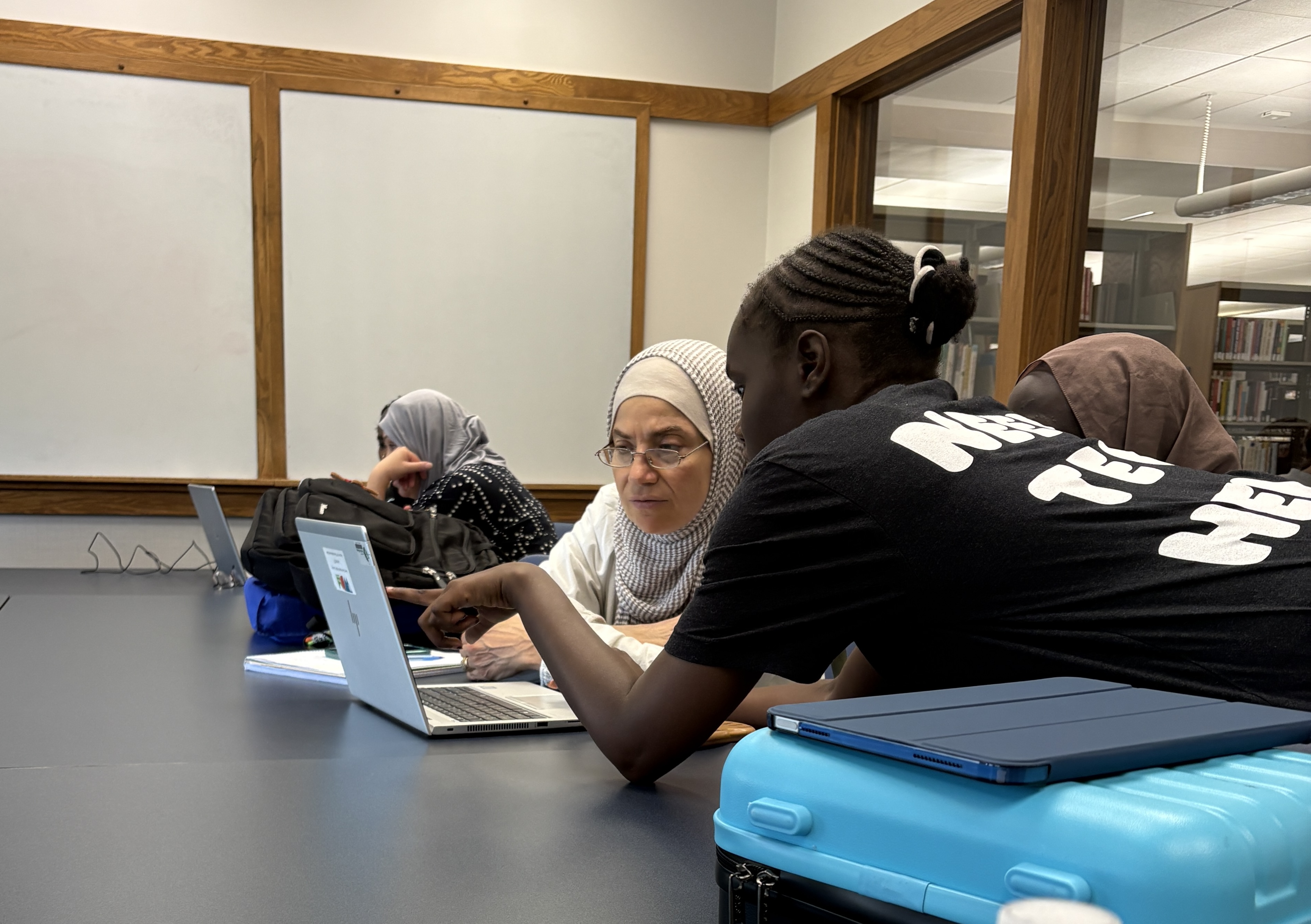 Teen trainer helping a community member with technology at West Des Moines Library