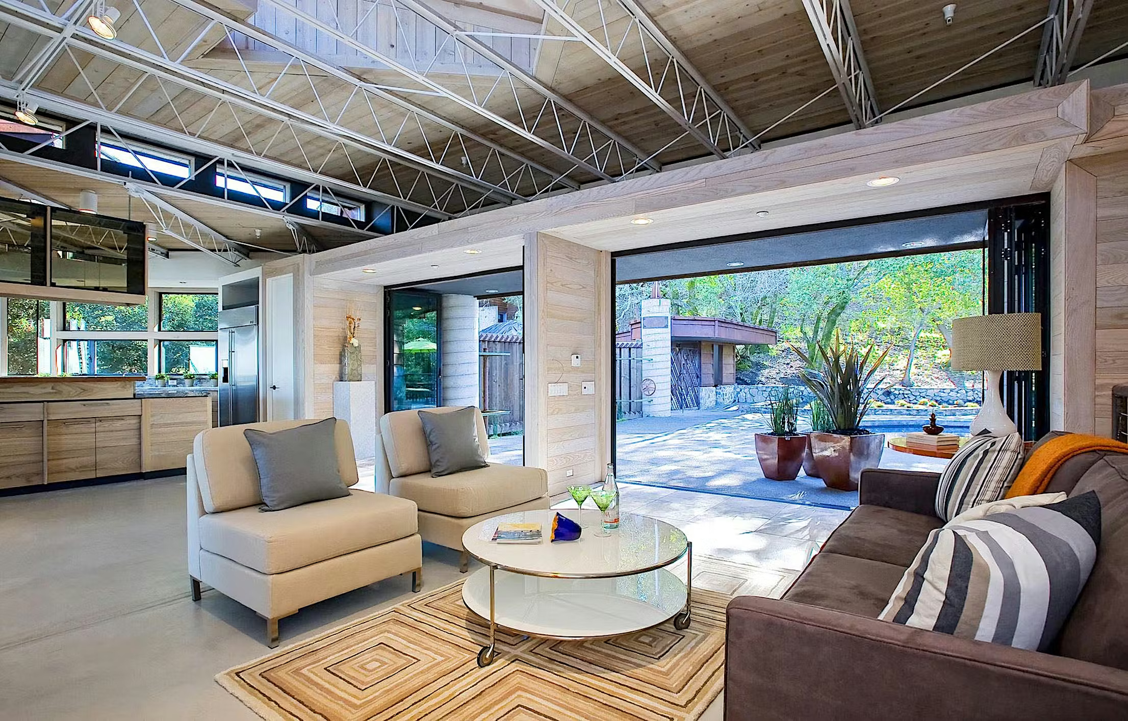 Glass living room extension featuring a spacious layout, modern furnishings, and large glass doors connecting indoor and outdoor spaces, designed for natural light and seamless garden views.