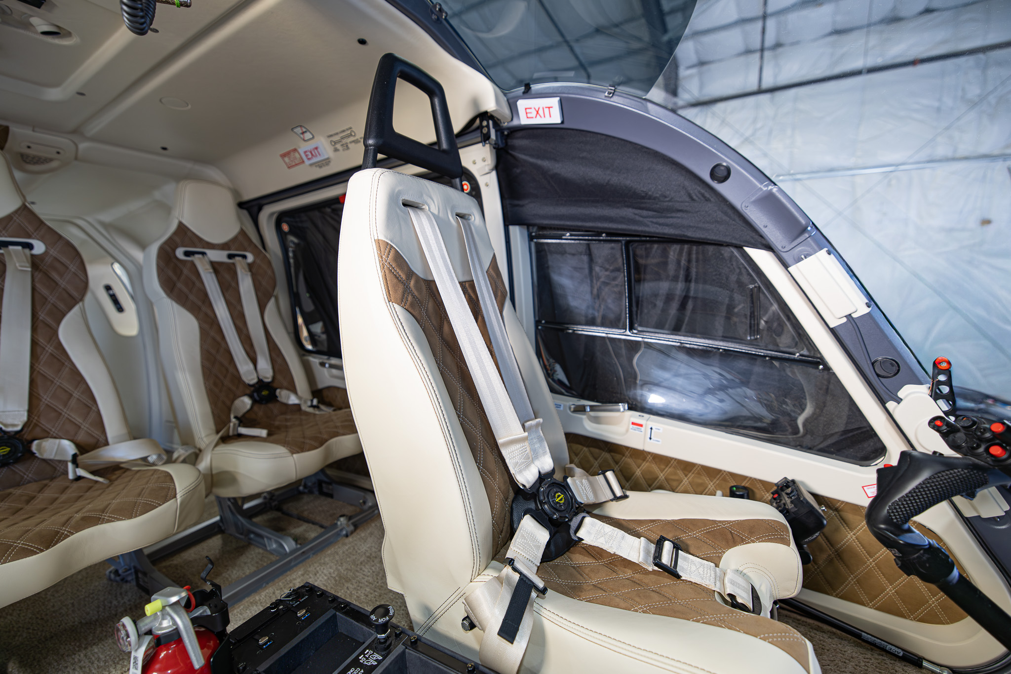 Pilot's seat with rear passenger seats in view, cream and brown leather