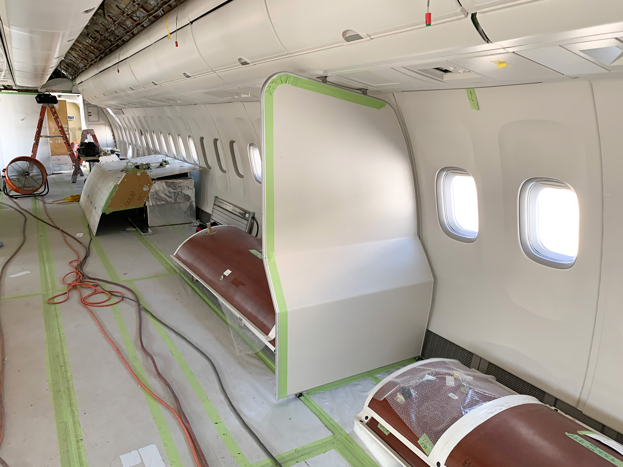 Cabin interior taped off with red leather seats covered, mid-prep