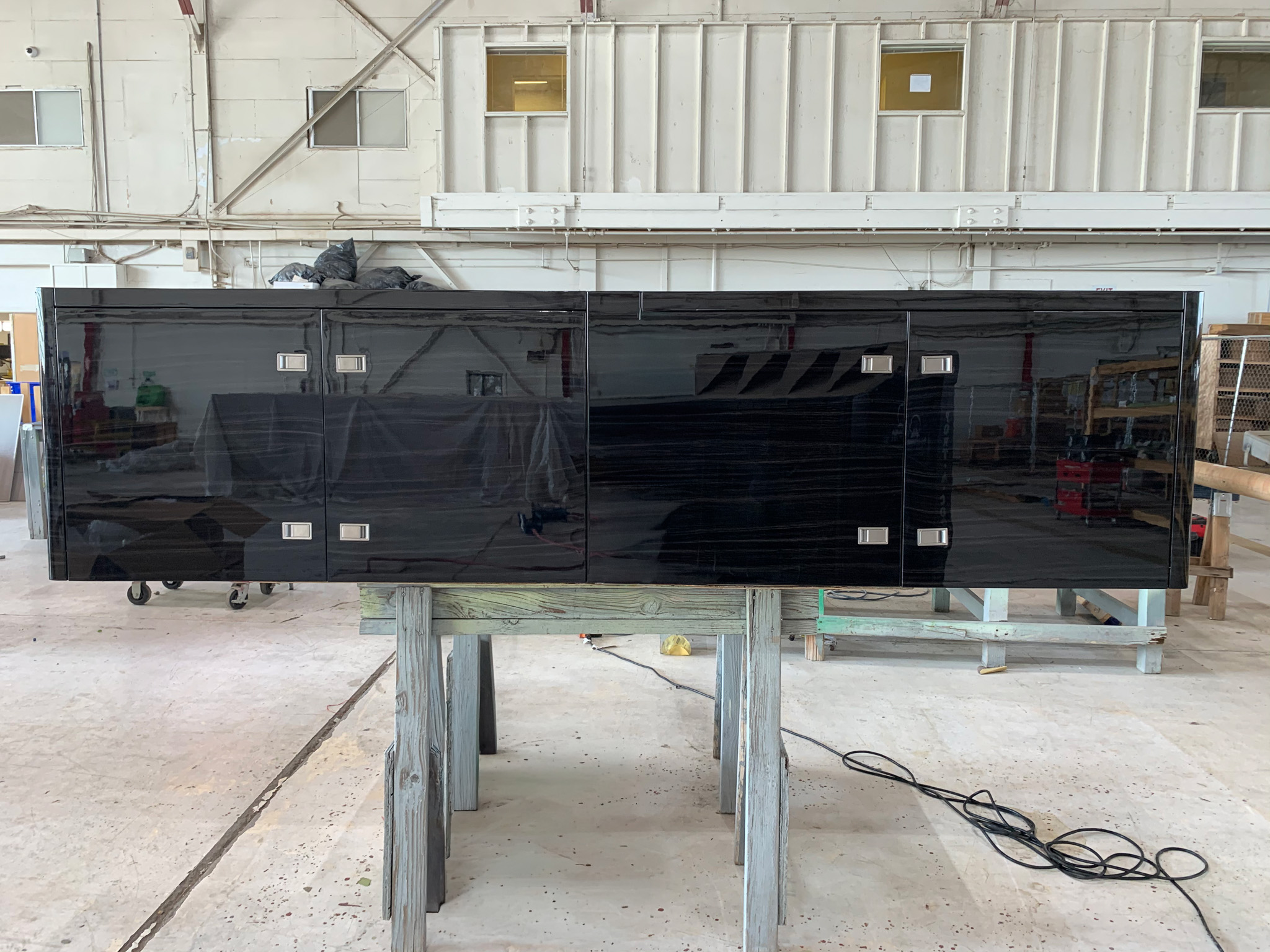 Custom black piano-finish credenza on sawhorses in the shop