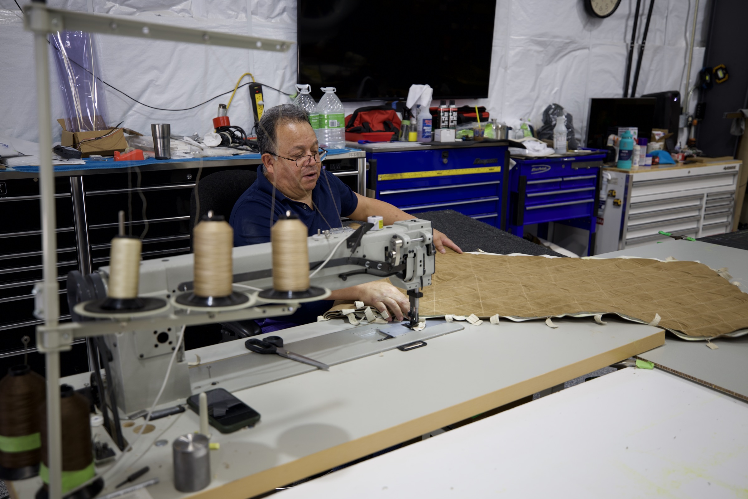 Technician hand-stitching a custom aircraft seat at Dynamic Designs Aviation