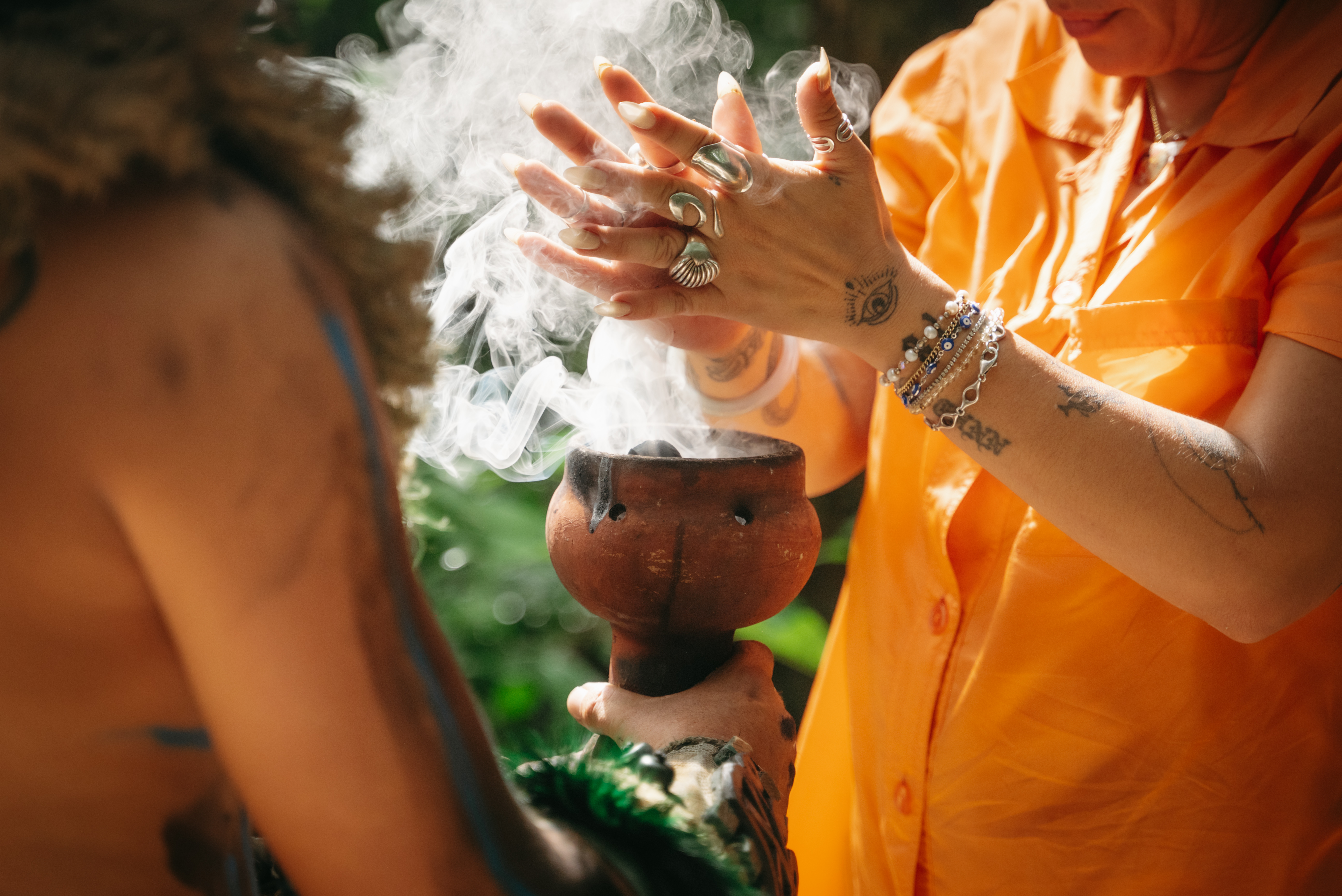 Hands offering copal smoke from a clay incense burner at sunrise