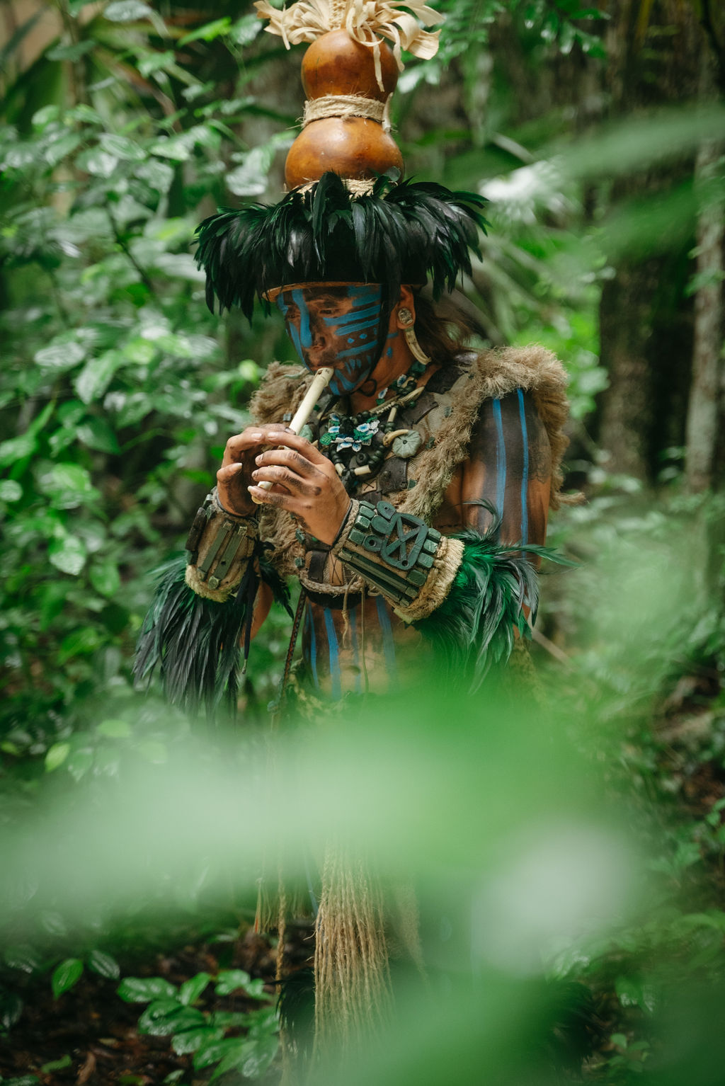 Shaman in traditional dress with feathered headdress performing a blessing