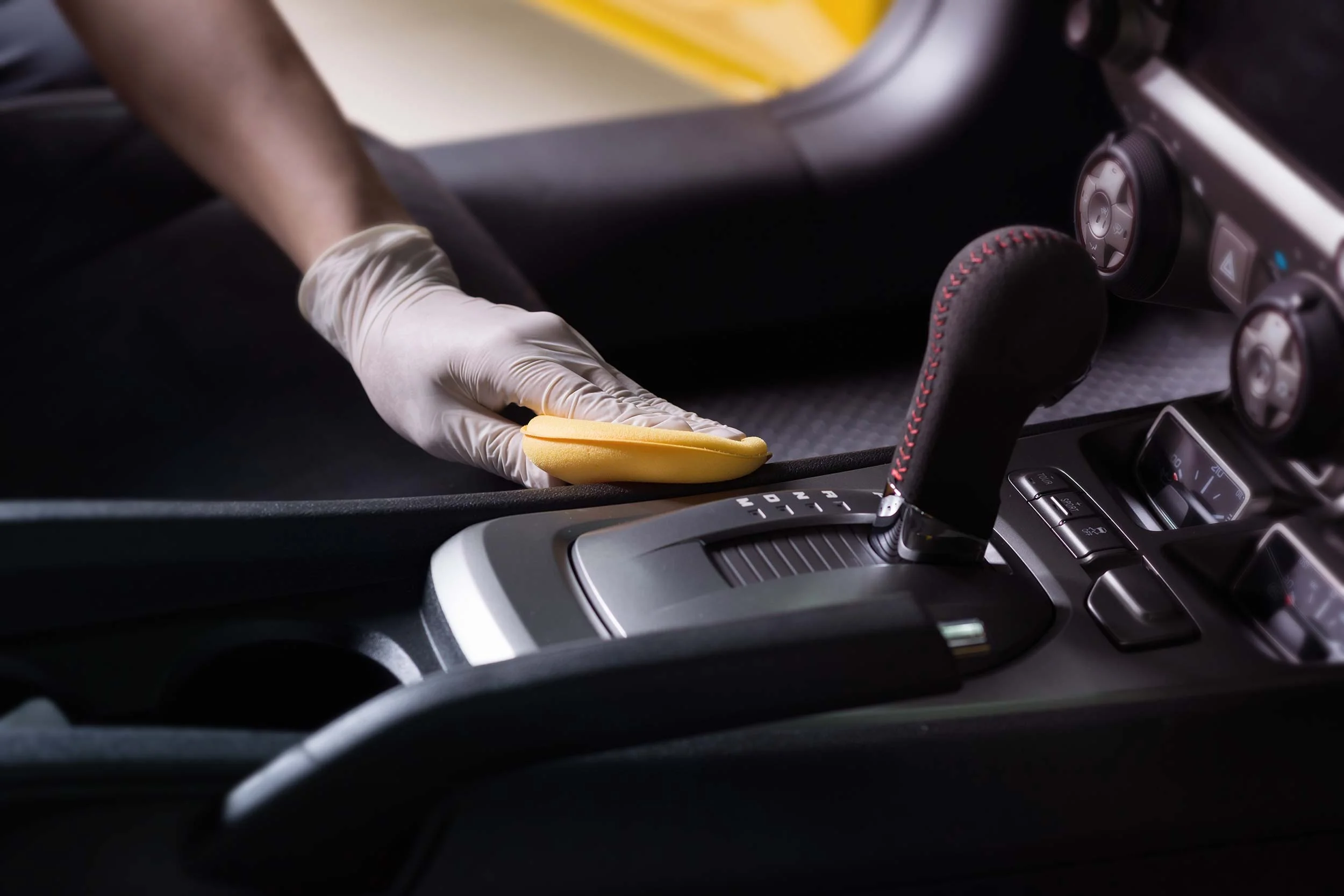 Gloved hand wiping down a center console