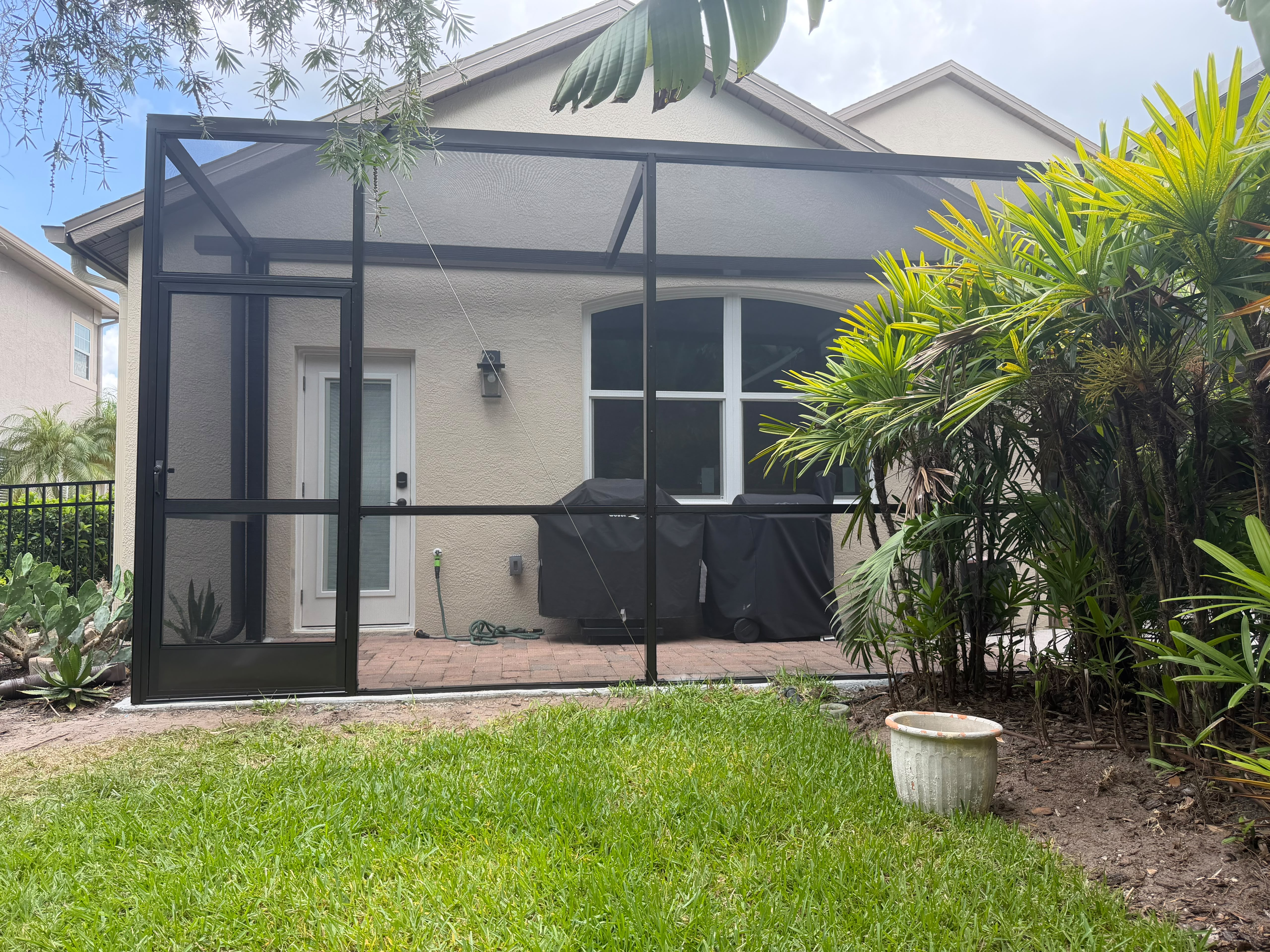 Screened porch beside a home and garden