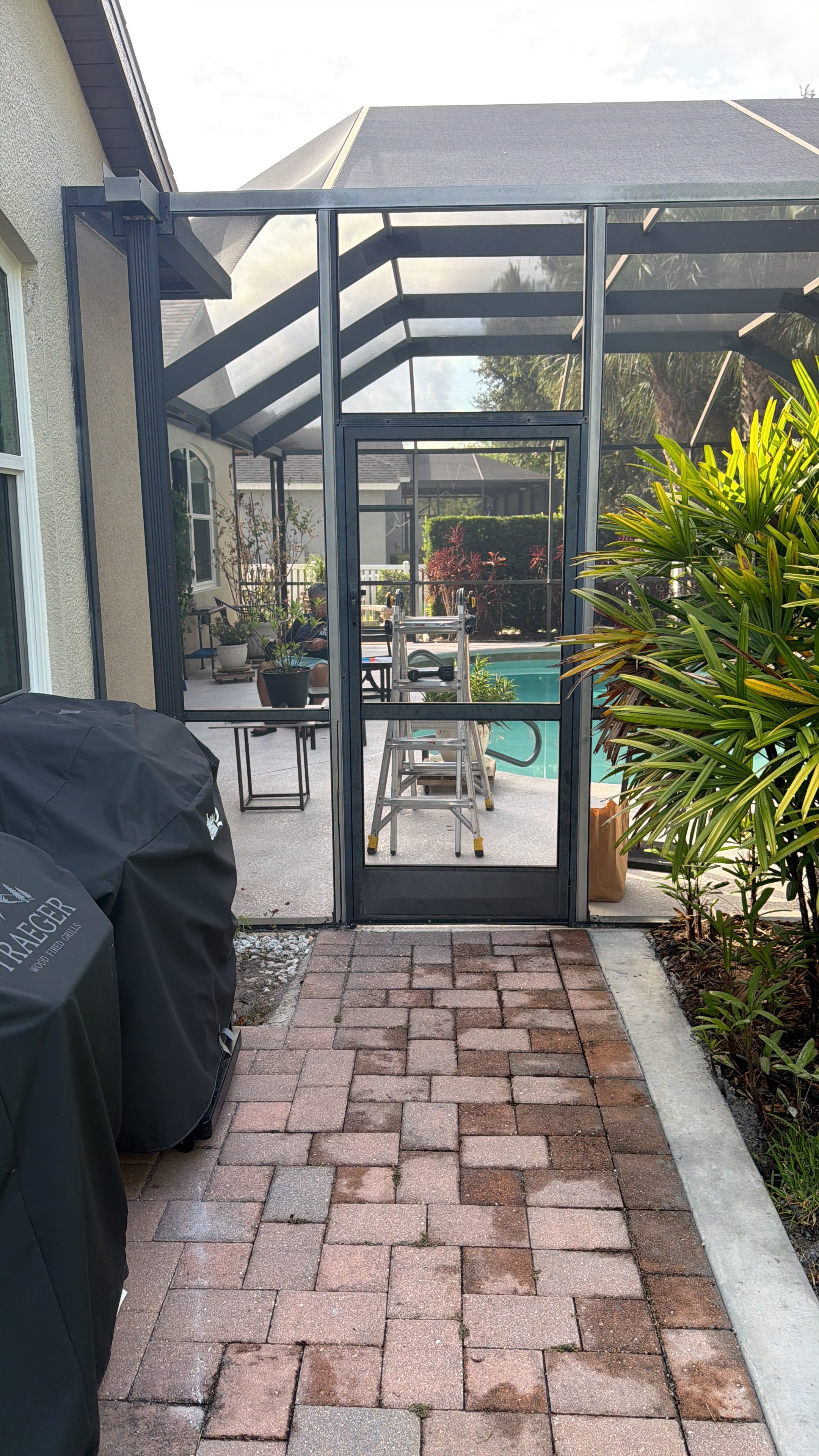 Screened patio with brick paving, dark framing and an access door