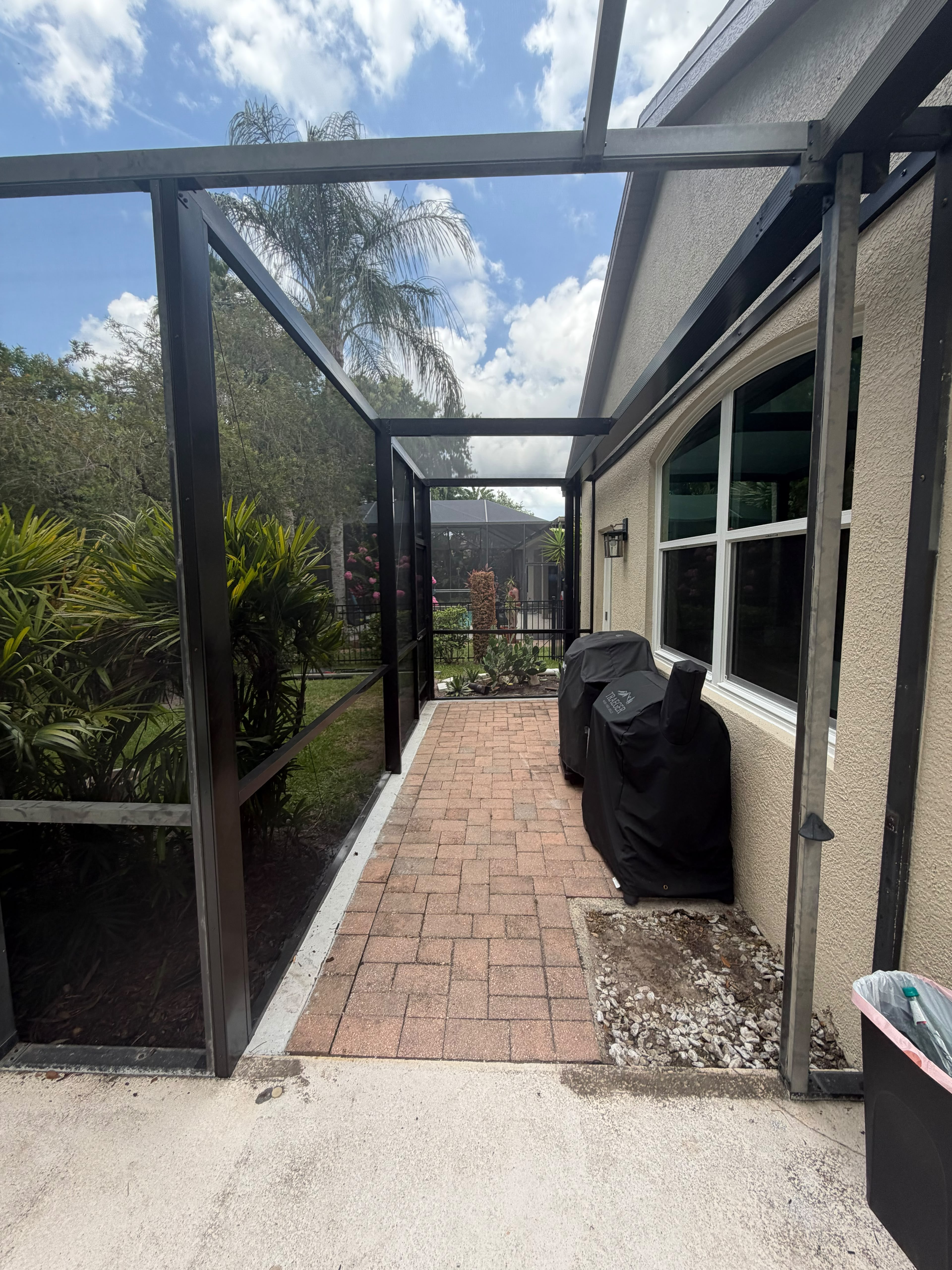 View along a screened outdoor walkway with dark frames and brick paving