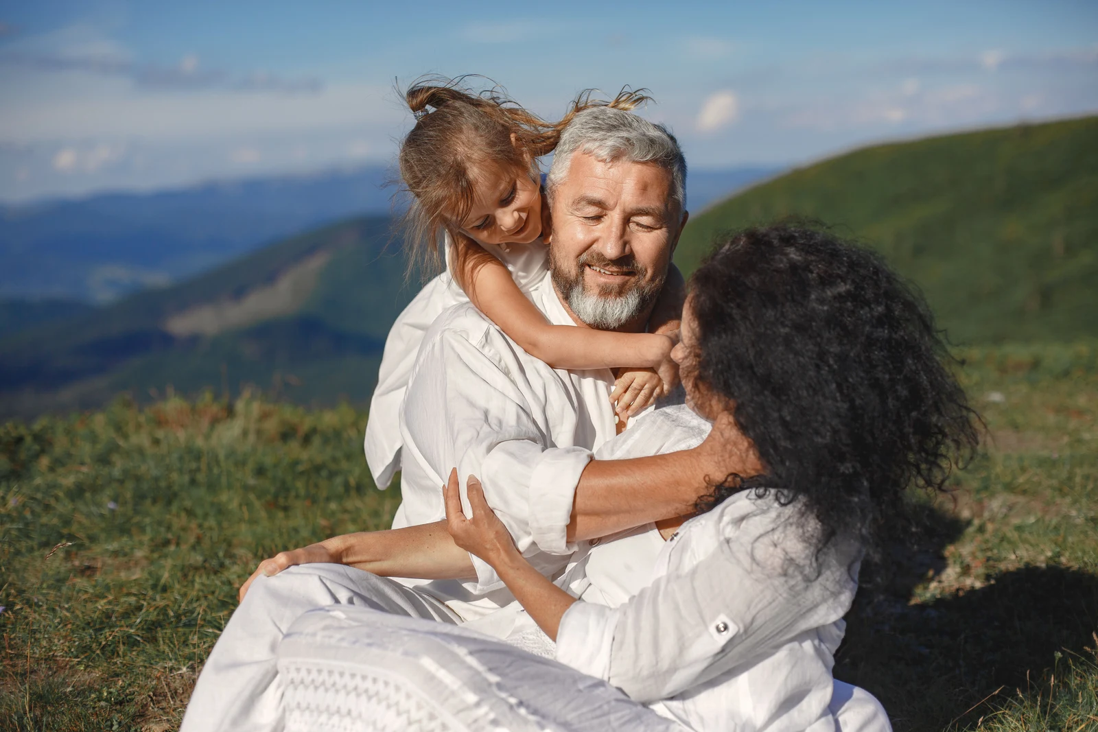 Grandparents sharing a joyful hug with their granddaughter outdoors