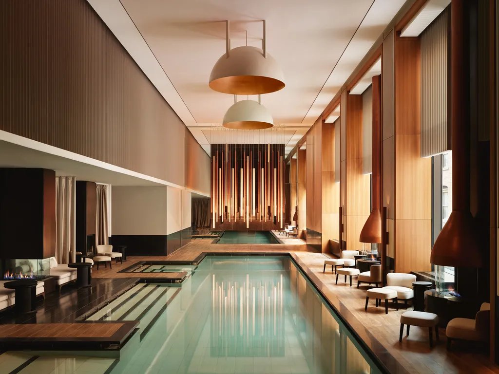 Resort-style indoor swimming pool with lounge seating, high ceilings, natural light, and luxury hotel-inspired amenities.