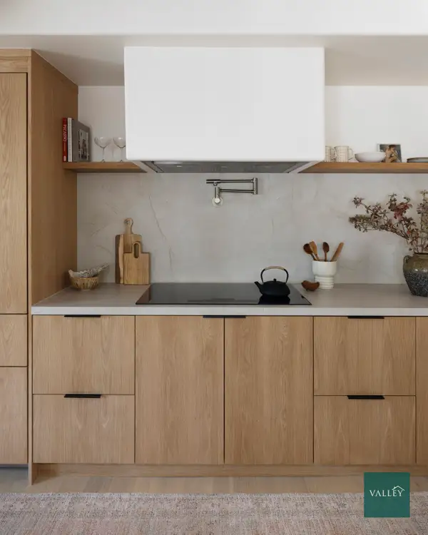 Modern minimalist kitchen with light wood cabinetry, integrated appliances, clean countertops, and contemporary design.