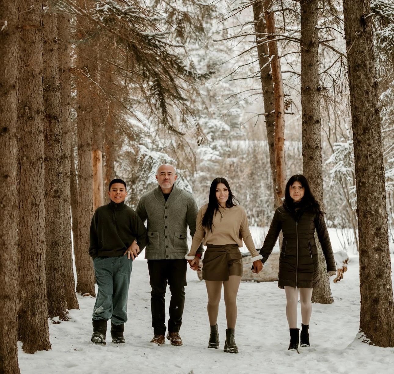 Hector walking through a snowy forest, hand in hand with his family