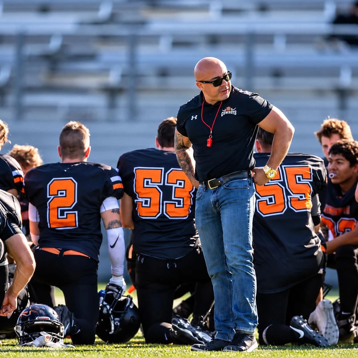 Hector with the Grande Prairie men's football team as players kneel on the field