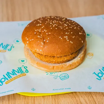 Crumbed chicken burger on Johnnie's teal-print wrapping paper