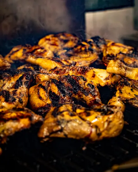 Chicken on the grill with smoke rising in the Johnnie's Windsor kitchen