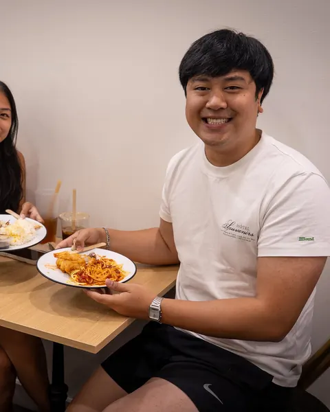 Smiling diners holding plates of Filipino food at Johnnie's in Windsor