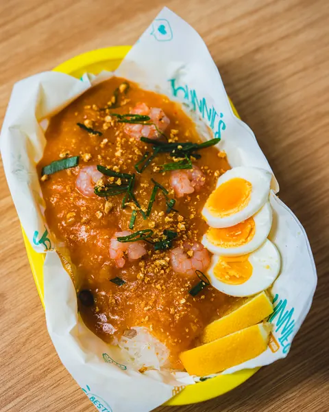 Palabok noodles with prawn sauce, boiled egg, chicharon and lemon in a yellow Johnnie's basket