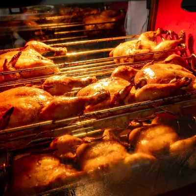 Whole chickens roasting in a warm-lit cabinet at Johnnie's Windsor