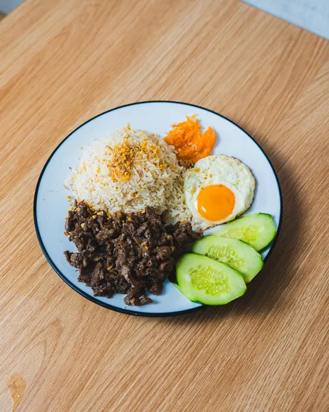 Tapsilog plate: beef tapa, garlic fried rice, sunny-side-up egg, atchara and cucumber