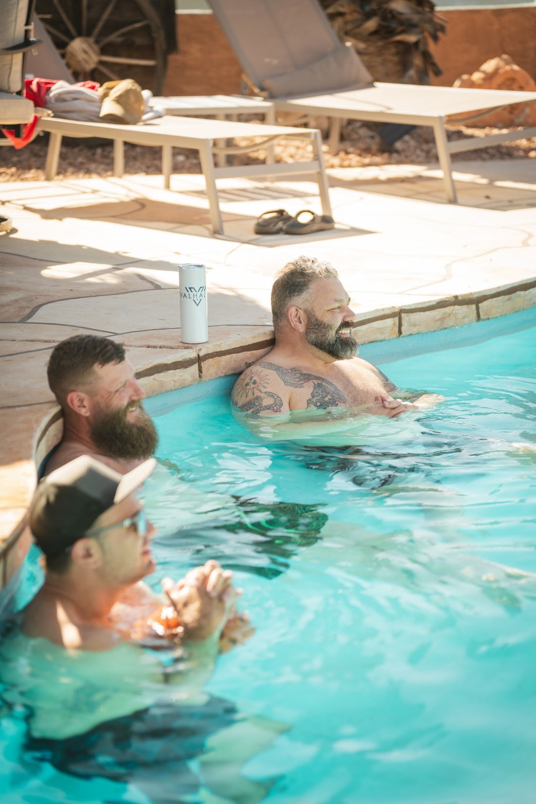 Two men talking with their backs against the pool wall