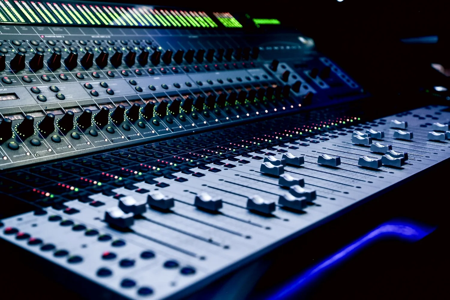 Professional audio mixing console with faders, knobs, and colorful LED indicators