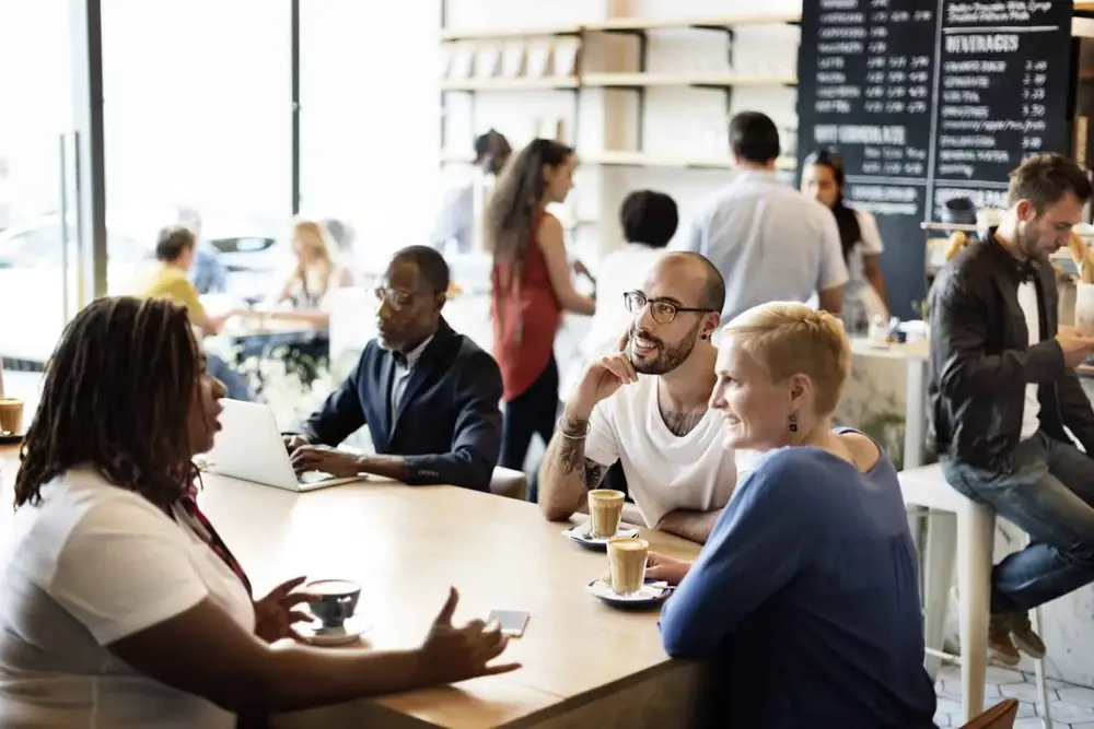 Friends talking over coffee at a busy coffee shop