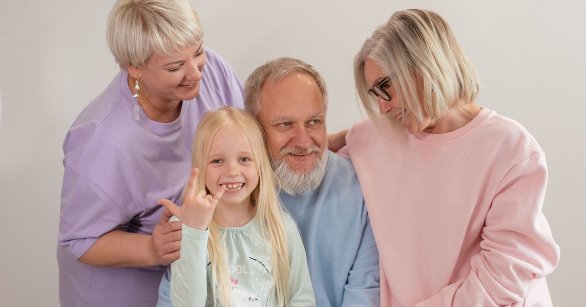 Multigenerational family with grandparents, parents and children smiling together indoors, representing a Super Visa family reunion in Canada