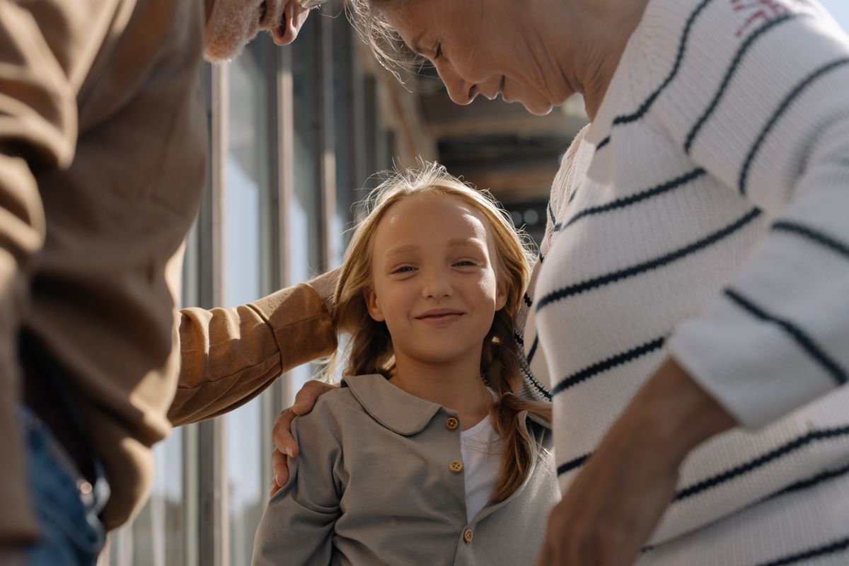 Smiling grandparents hugging their granddaughter, representing families reunited through a Canadian Super Visa