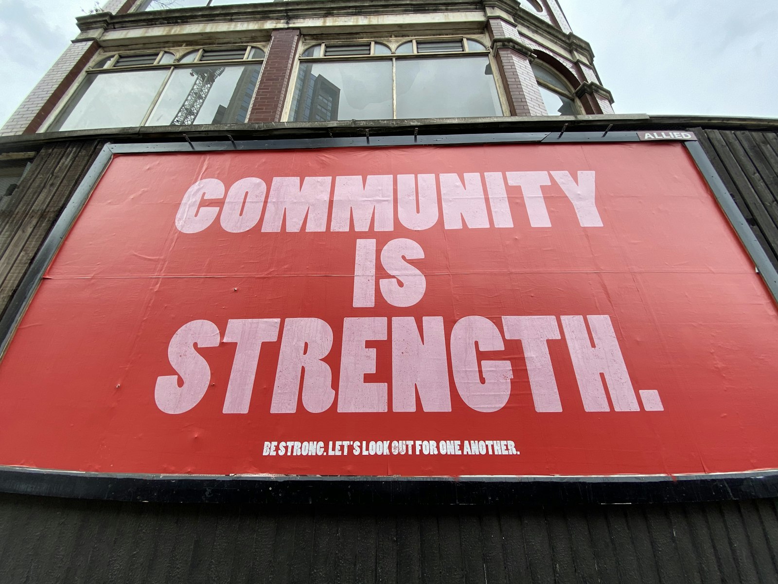 A red billboard with large white text reading Community Is Strength, representing community impact built into everyday operations
