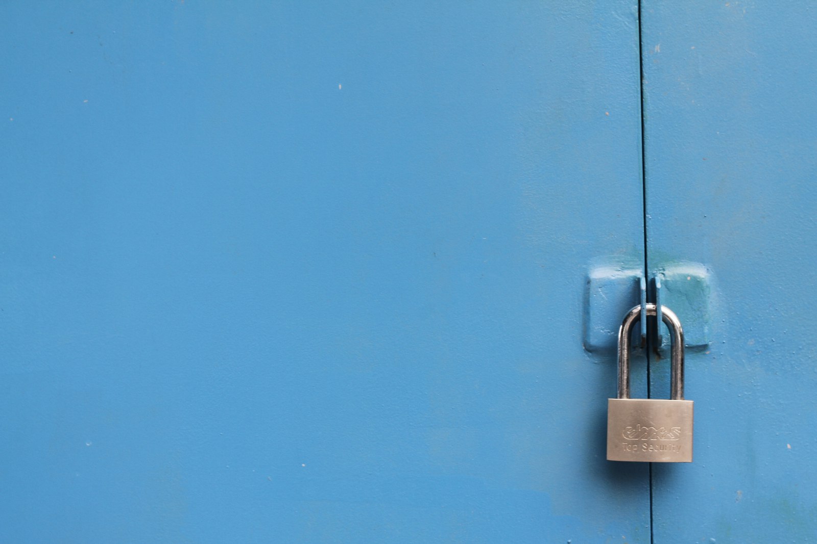 A silver padlock on a blue-grey surface, representing creditor protection when surplus cash sits in a separate holding company