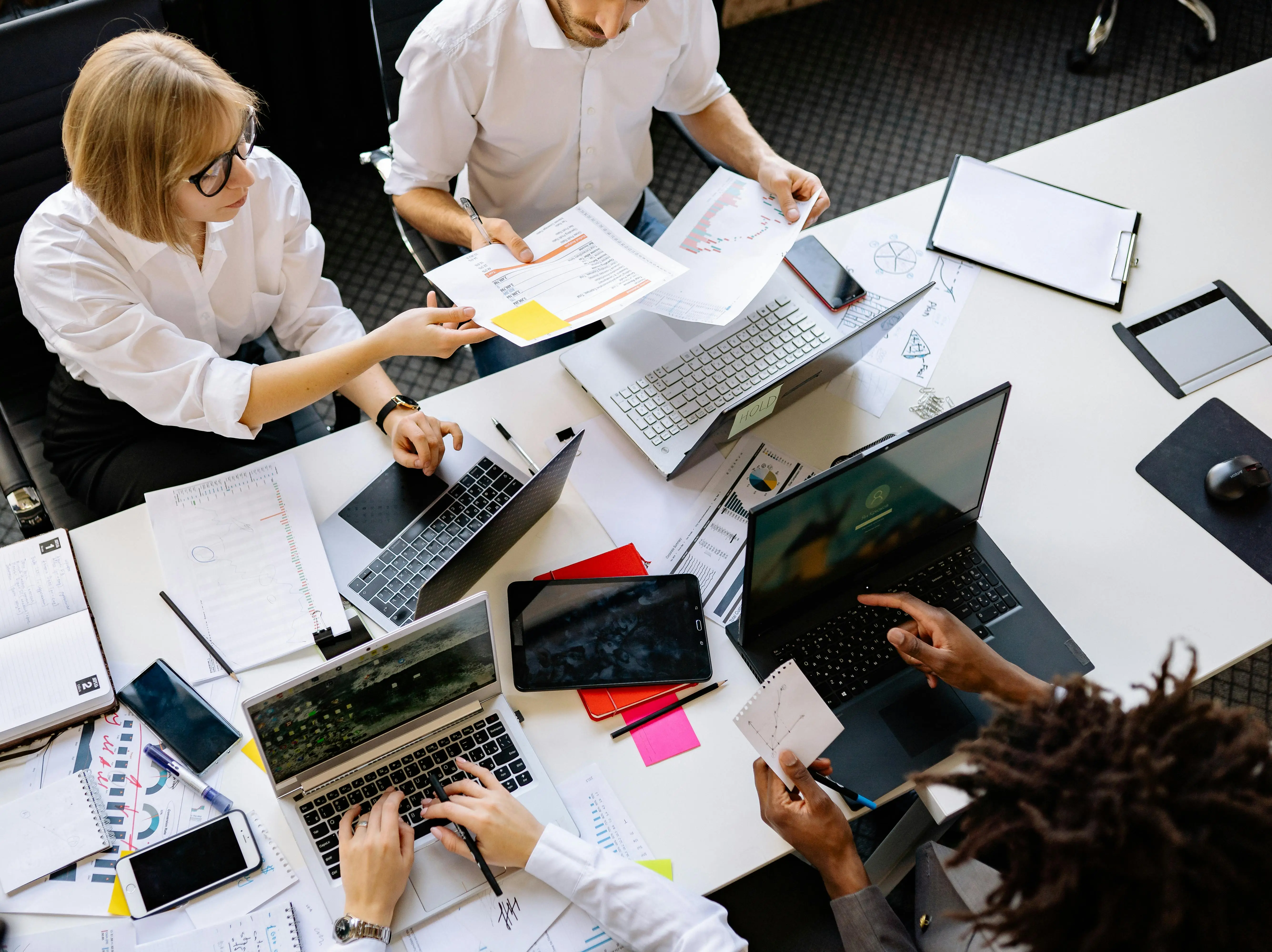 A cross-functional team works simultaneously on multiple laptops — the kind of parallel execution that documented systems make possible