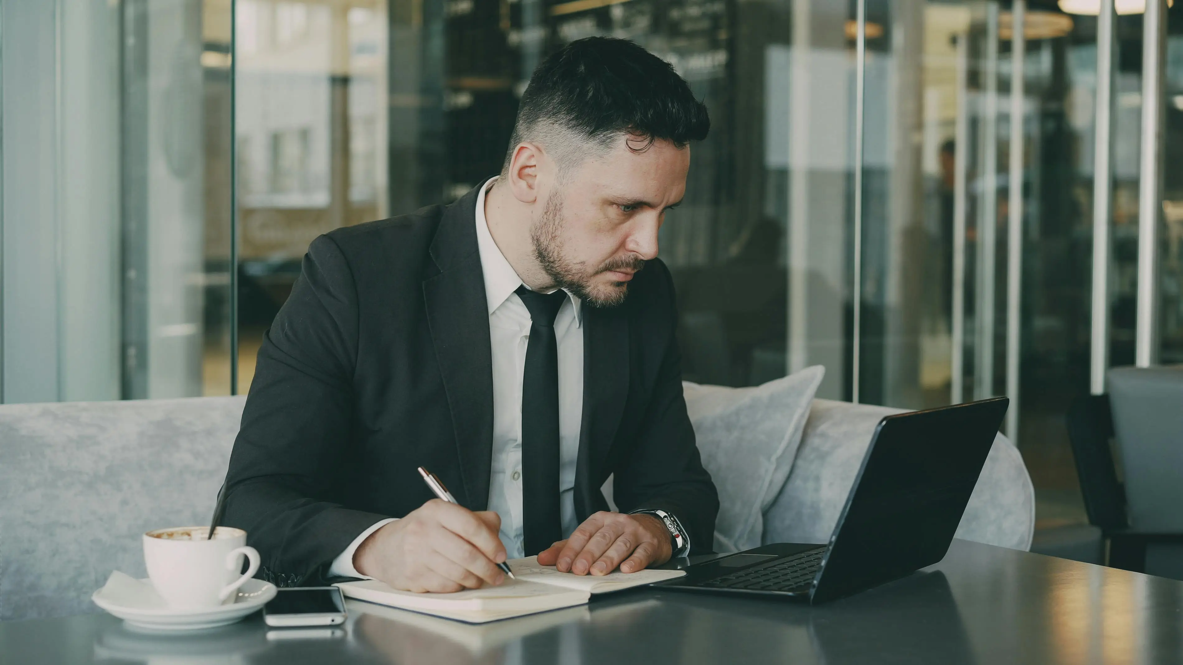 A confident entrepreneur working relaxed at an outdoor café, representing the freedom that comes when AI systems handle operational and content workflows independently