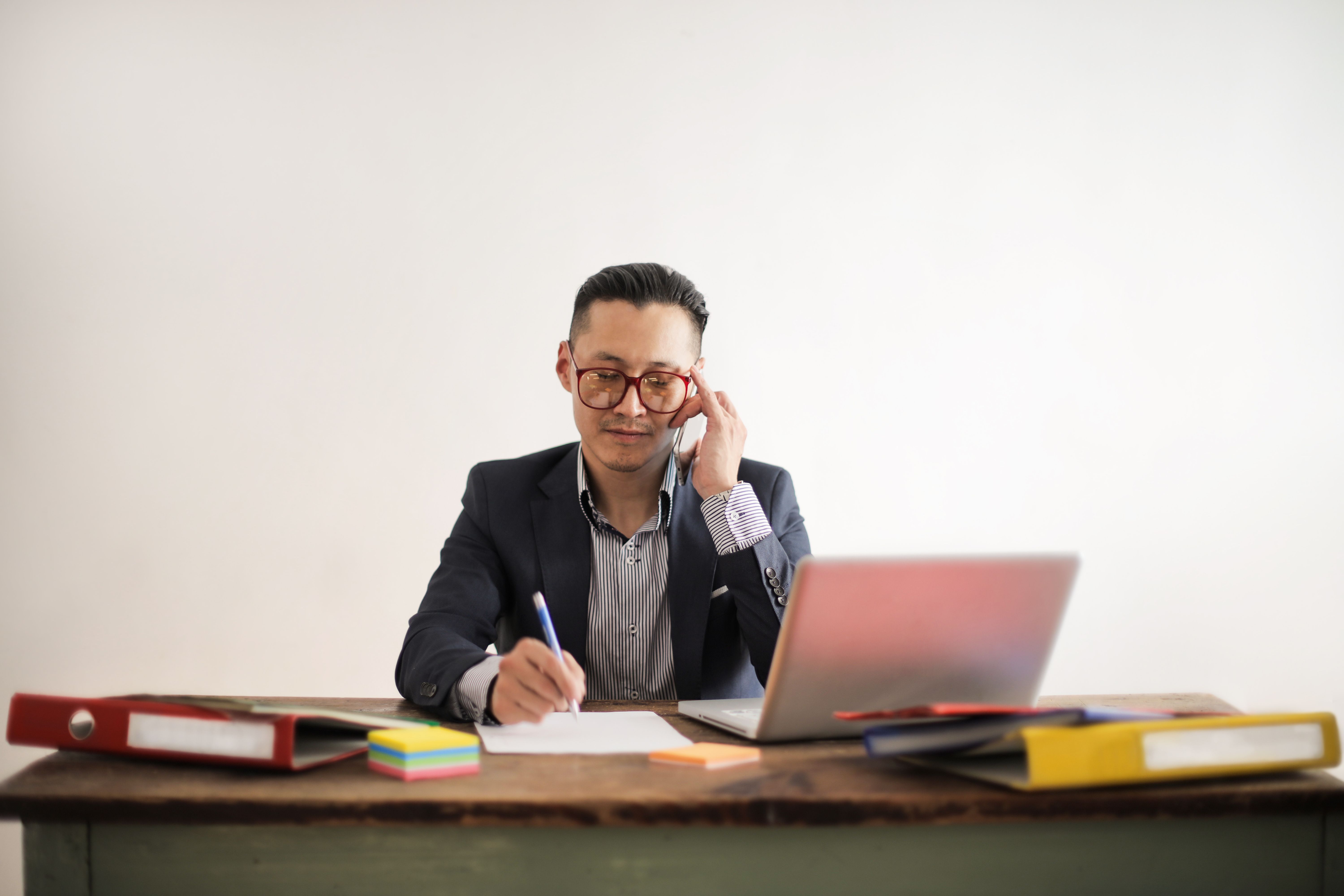 Focused entrepreneur working on a laptop and smartphone at a modern desk — representing the side hustle phase of building a business while still employed