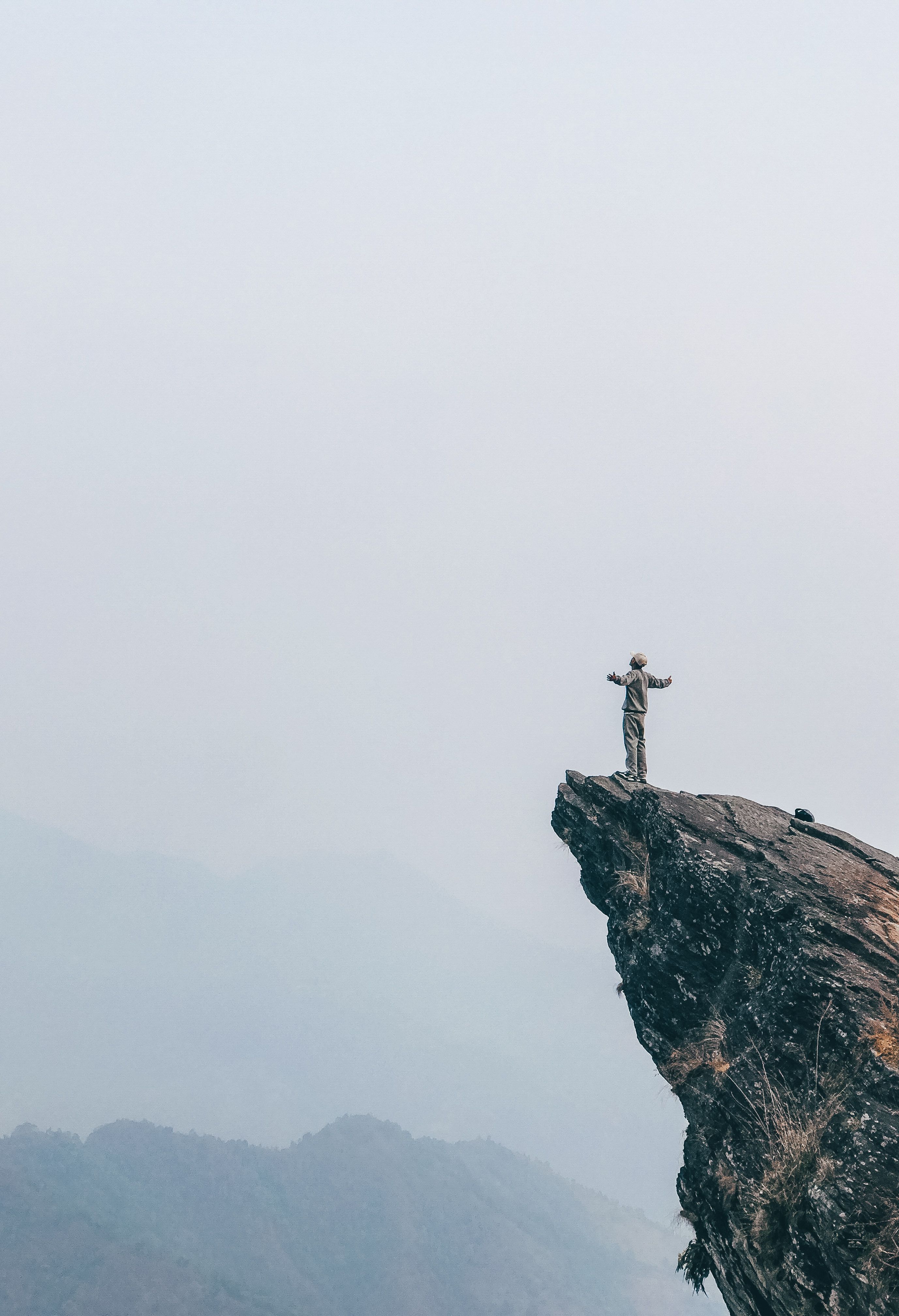 Hiker standing at the edge of a dramatic cliff overlooking open wilderness — representing the bold decision to leave security and bet on yourself as an entrepreneur