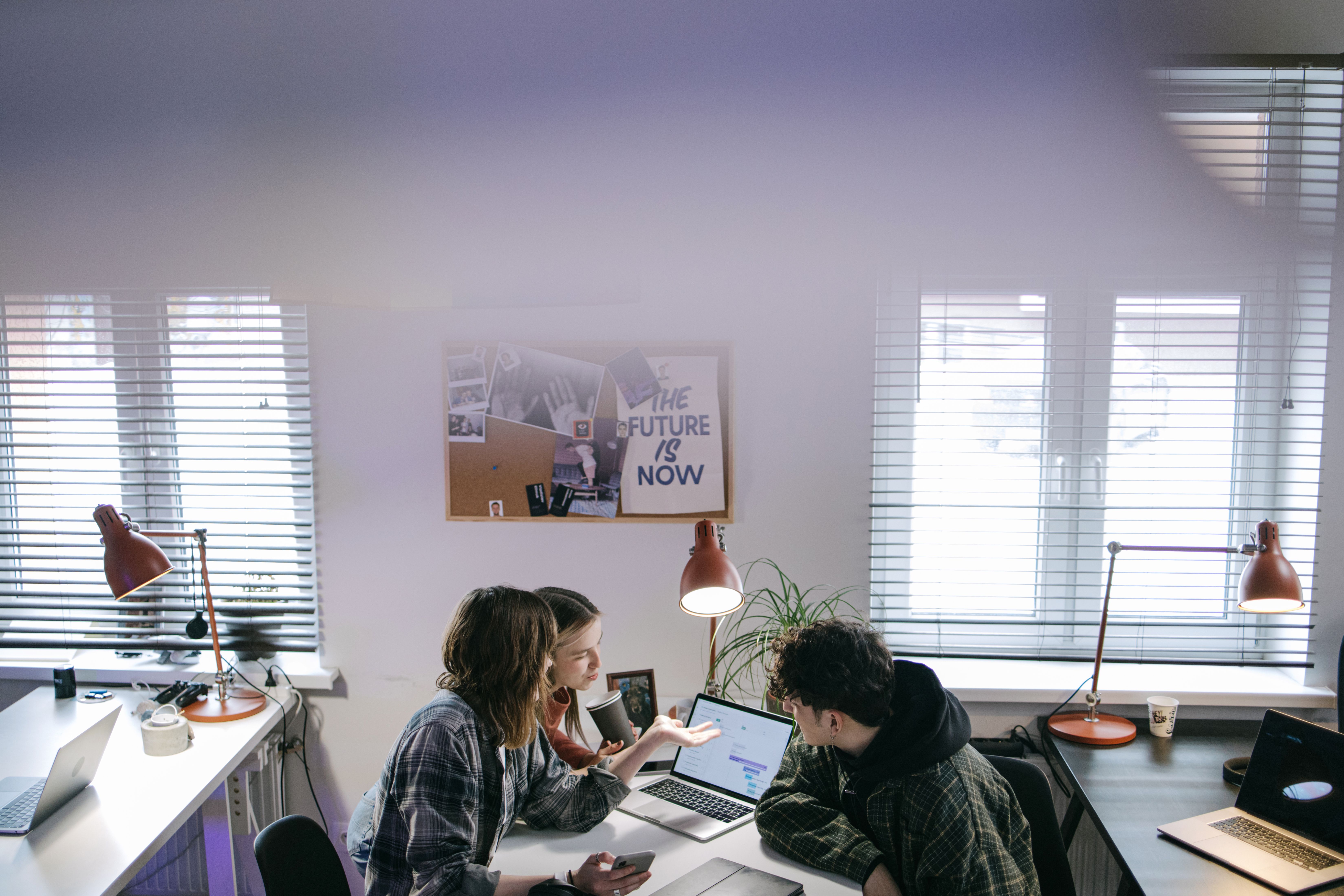 Two colleagues smile and high-five at a shared workstation, representing successful team onboarding and early employee engagement driven by AI-assisted onboarding workflows
