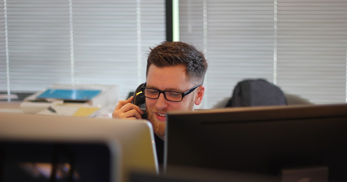 A small business owner glances at a smartphone showing multiple missed call notifications, representing the scope of the missed call problem for SMBs that lack 24/7 phone coverage