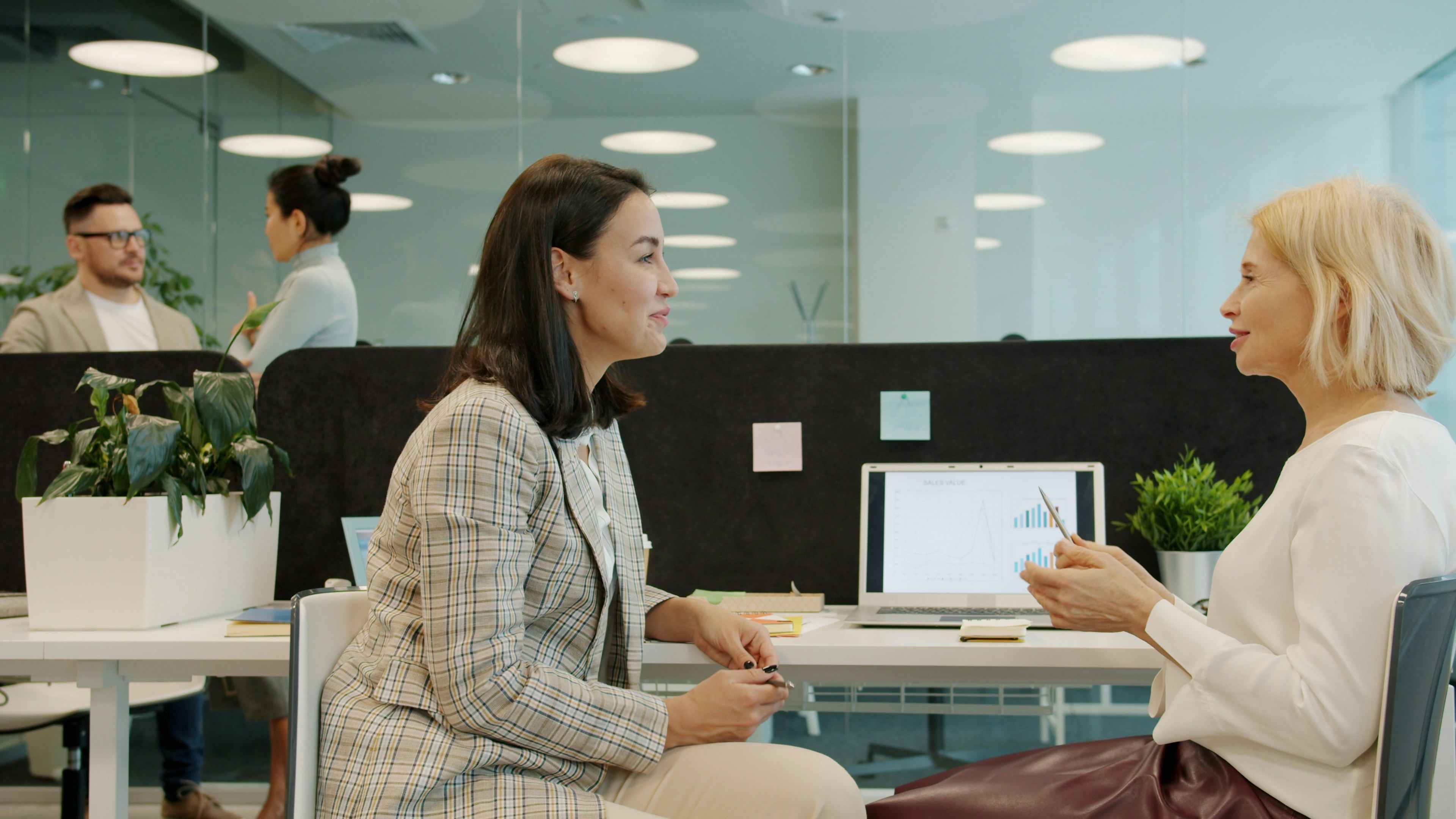 Two business professionals review a printed report with charts at a table, representing a company assessing the financial impact of an unmanaged AI security incident