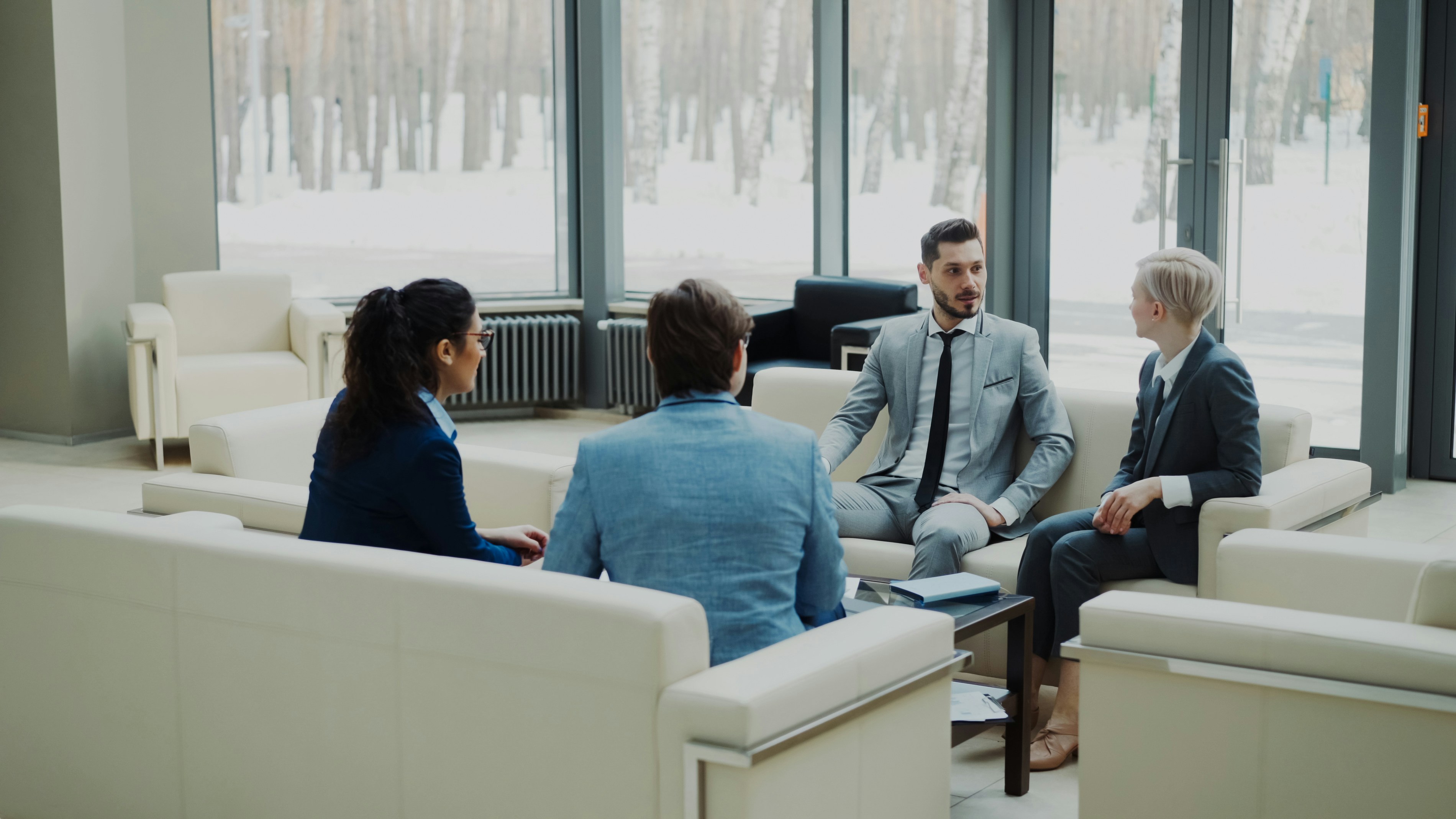 A small team sits together in a modern office discussing a document, representing a leadership team building an AI usage policy collaboratively