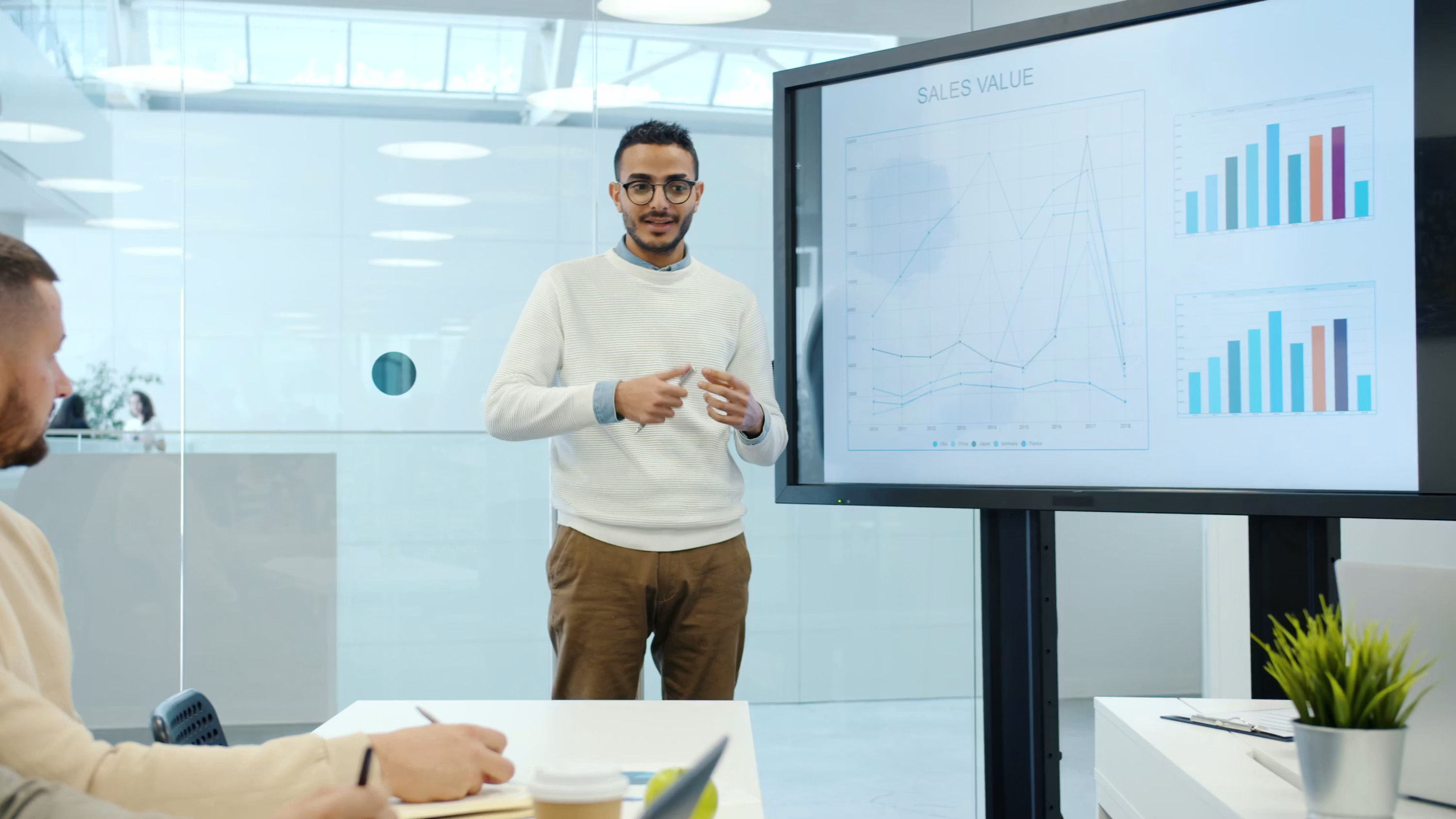 A presenter walks a small team through revenue charts on a screen during a meeting, representing how AI cash flow forecasts get reviewed and acted on