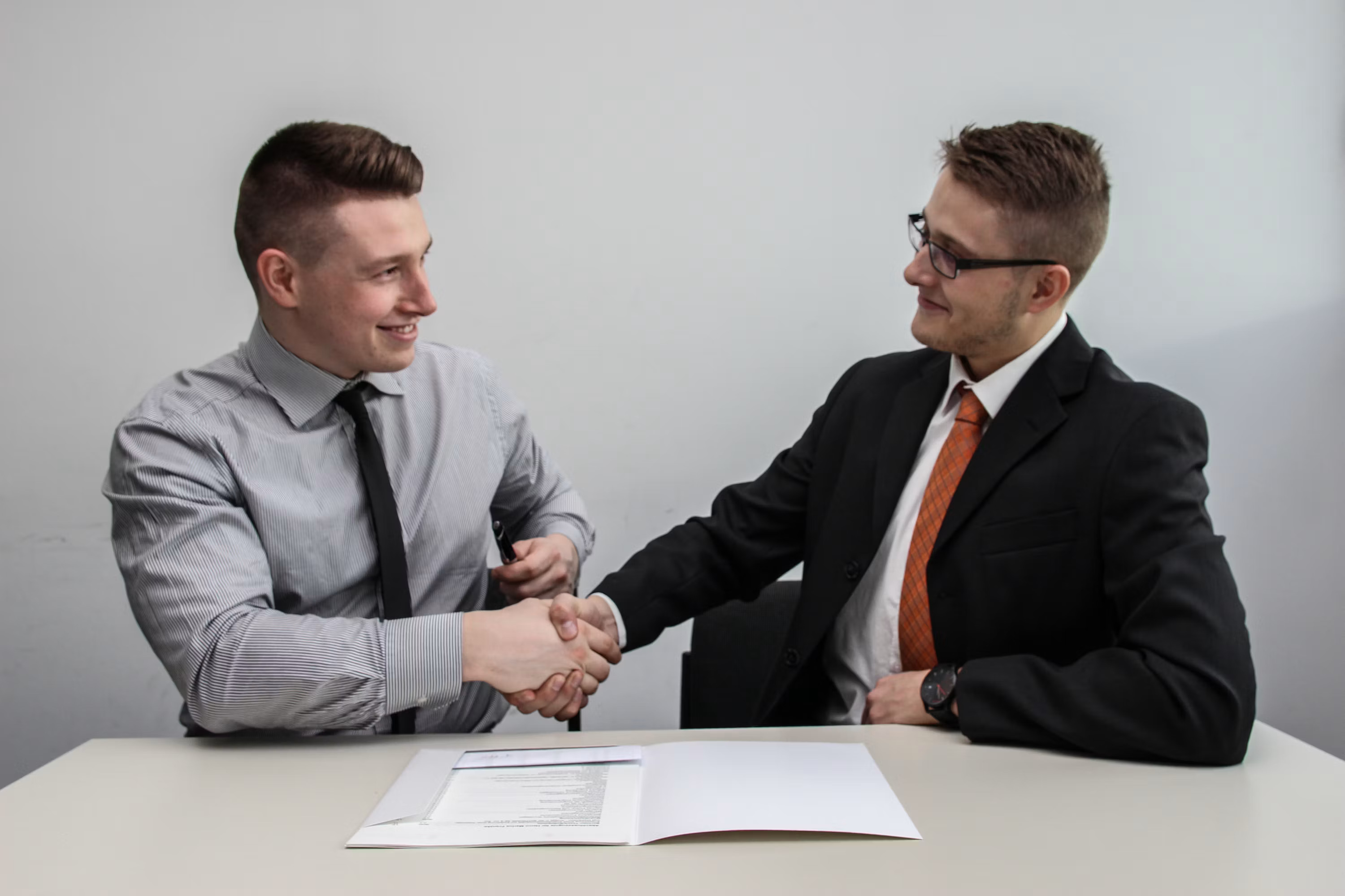 A technician and a homeowner shake hands and smile after a completed job, representing the outcome of a faster quote-to-close process powered by AI
