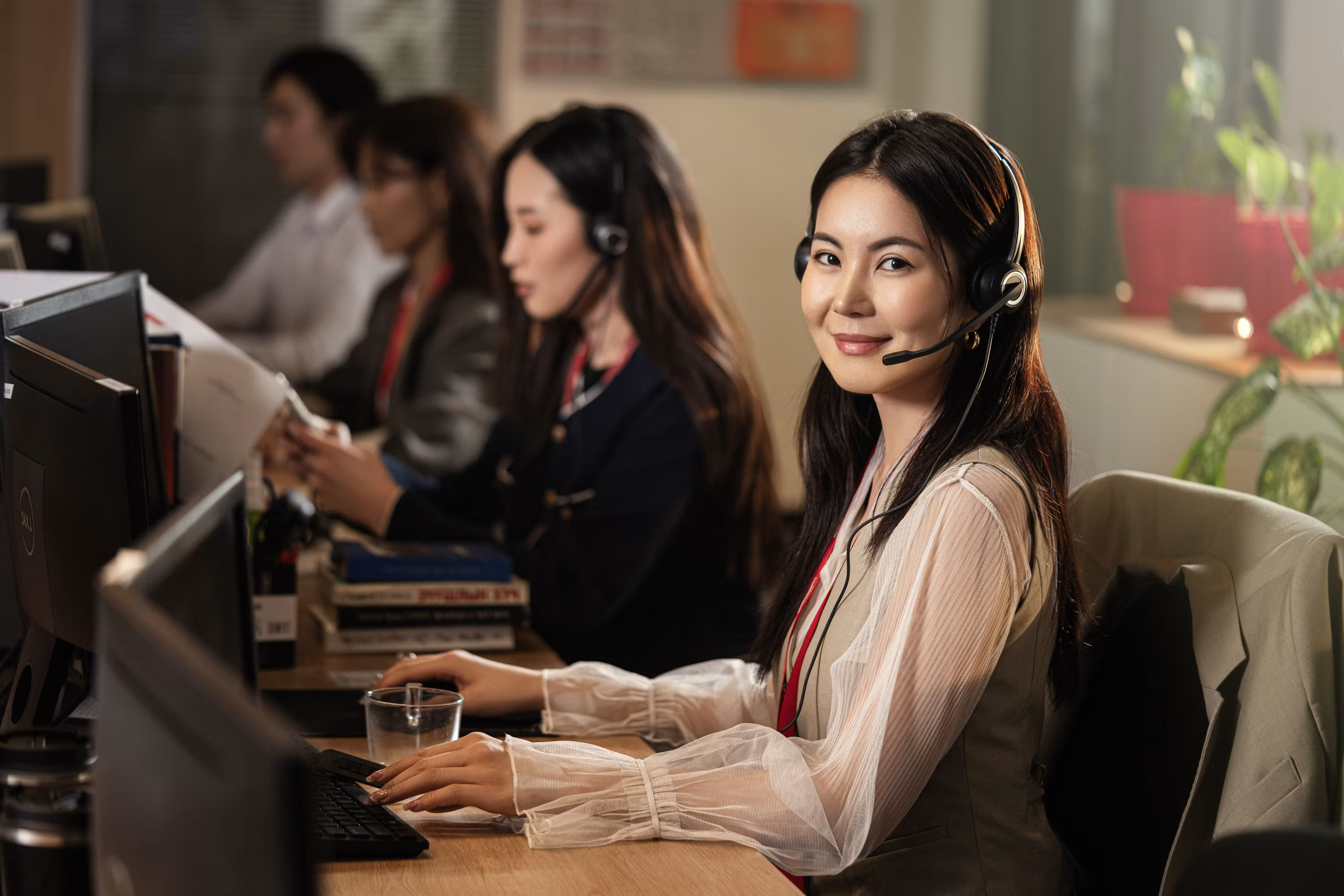 A customer service representative wearing a headset smiles while talking with a caller, representing how AI phone agents now handle the first response for home service businesses