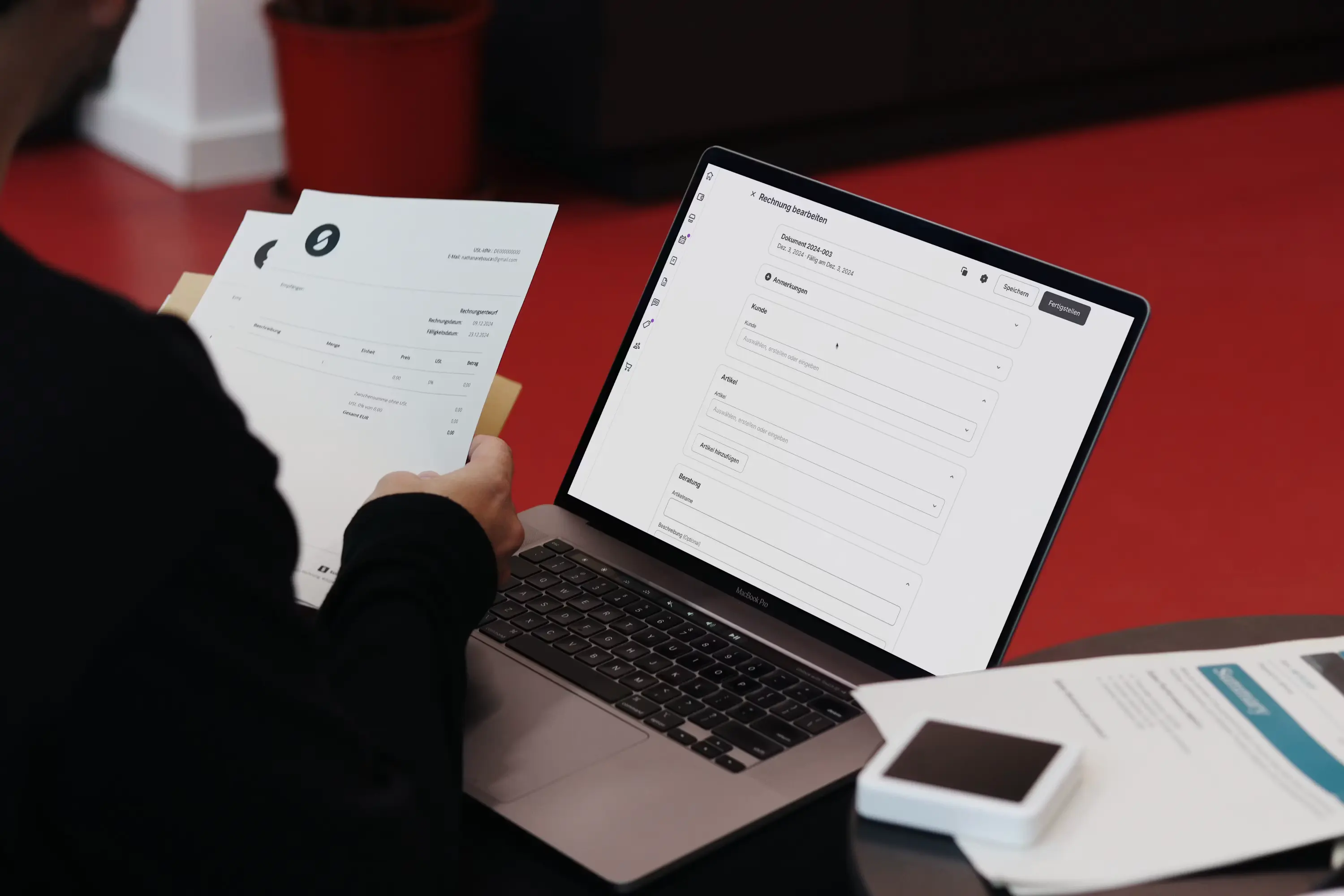 A person at a desk holds a paper document next to an open laptop showing a digital invoice system, representing the shift from manual paperwork to AI-extracted data