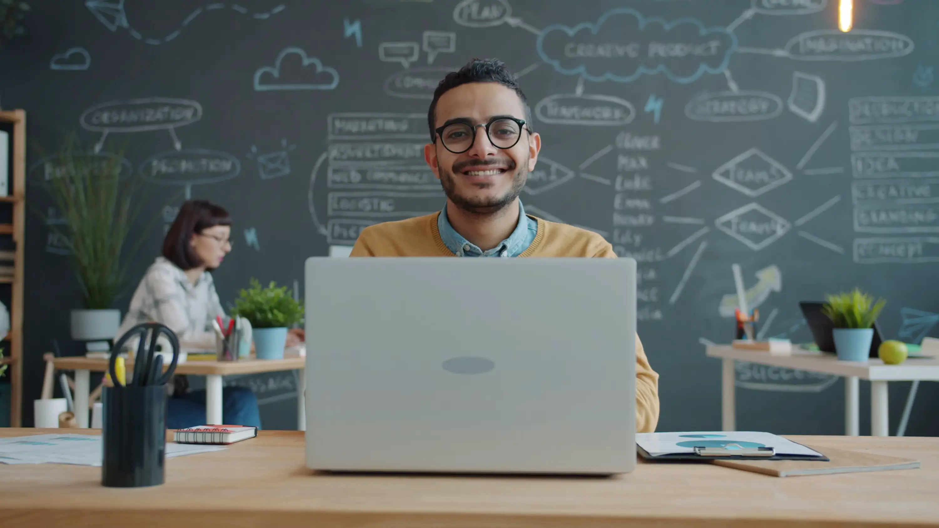A man smiles while working on a laptop in a modern office, representing the time and stress recovered once AI document processing replaces manual invoice entry