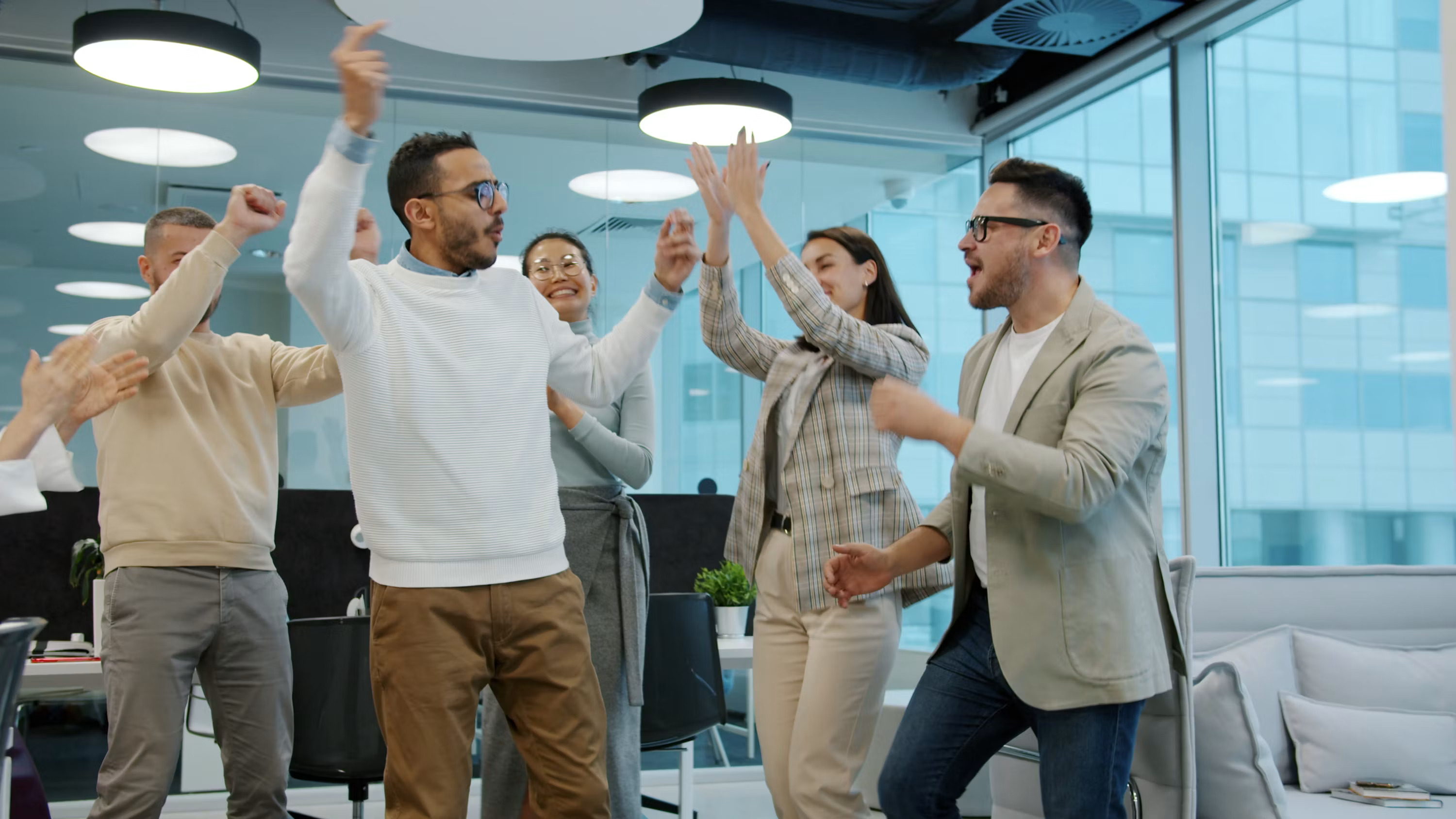A diverse group of colleagues celebrating success in an office, representing the confidence that comes from building an AI stack on vendors built to last