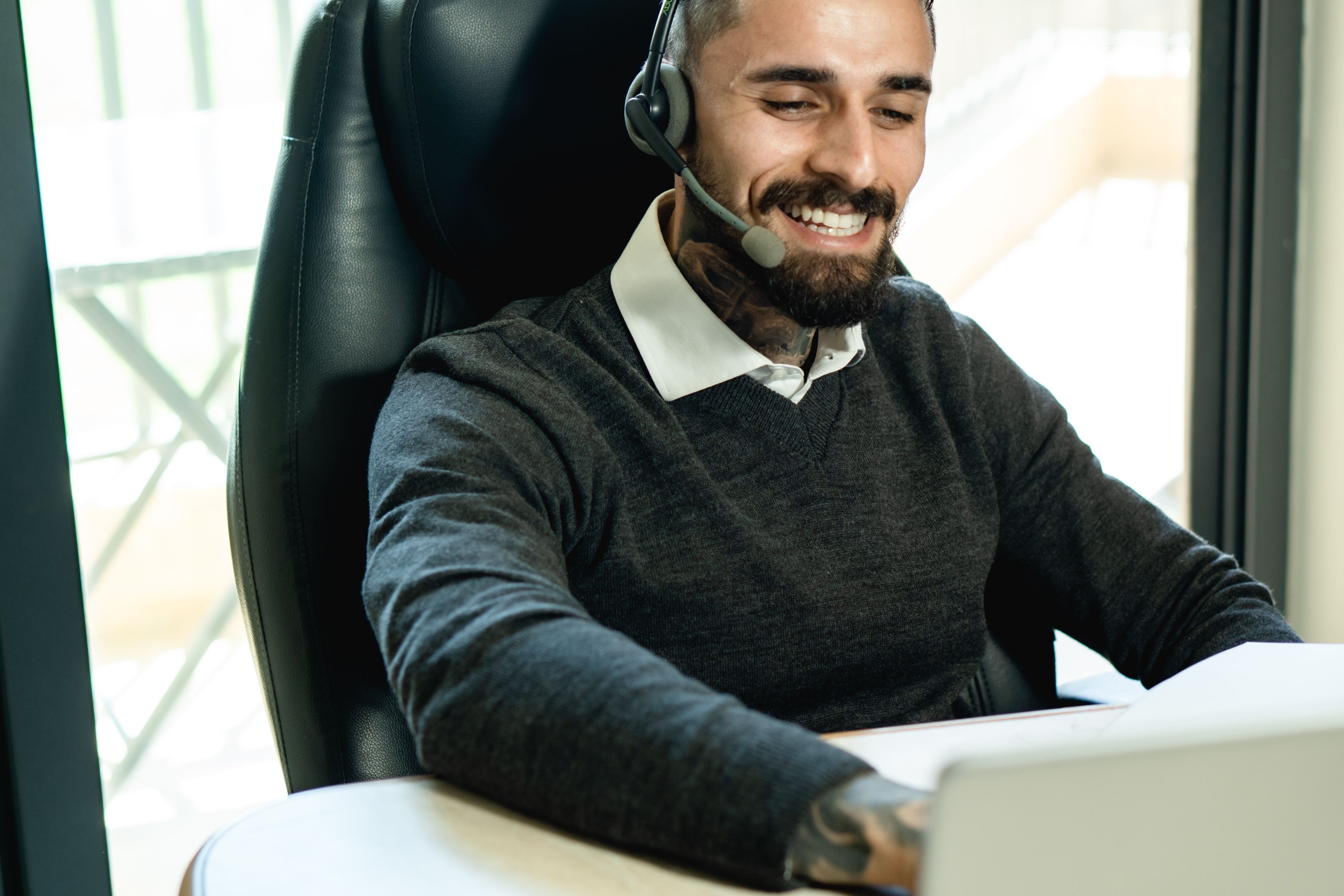 A customer service representative wearing a headset answers calls at a modern office desk