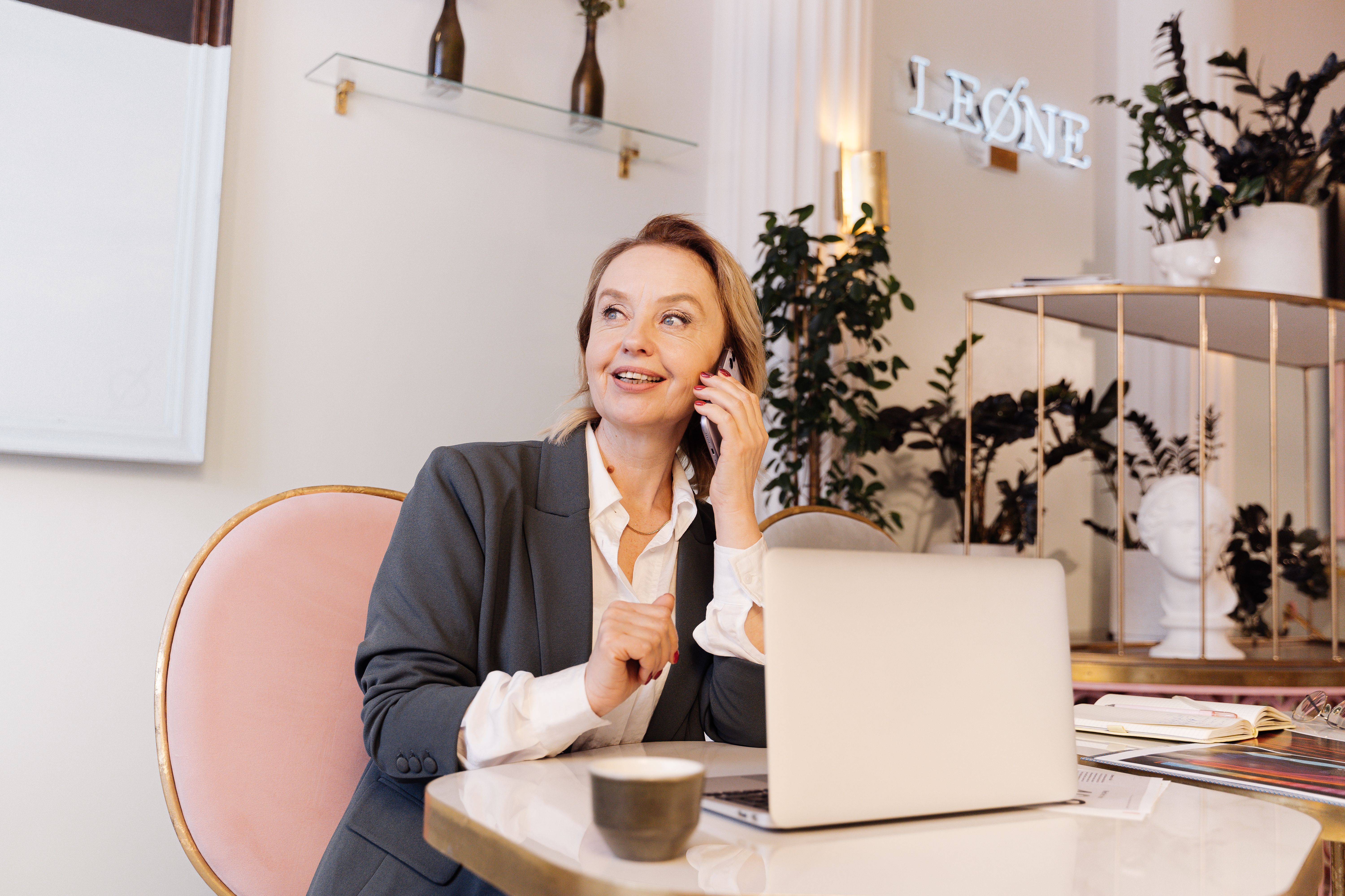 A businesswoman speaks on the phone at her desk while reviewing information on her laptop