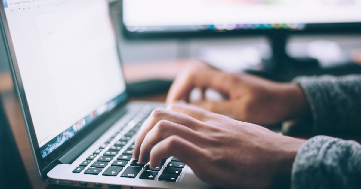 A person using AI software on a laptop at a desk in a small office