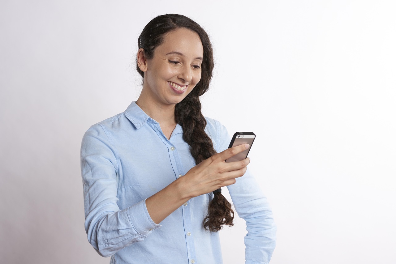 A person smiling while texting, sharing a business recommendation with a friend on their phone